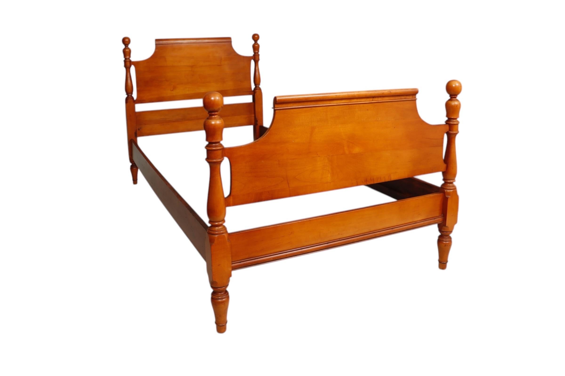 A Colonial style twin bed frame made of maple. Turned baluster bed posts are topped with cannon ball finials, and support slightly scrolled head and foot boards.
