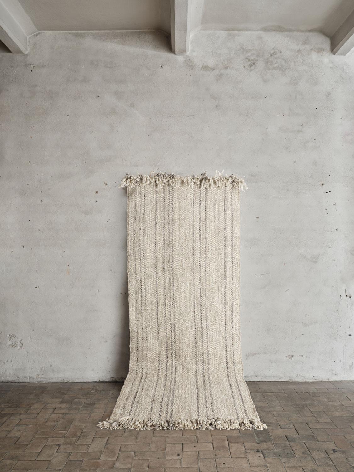 Colonnade no.06 Rug by Cappelen Dimyr
Dimensions: D 100 x H 240 cm
Materials: 100% Wool 

Colonnade no.06 is a hand-woven wool rug designed for narrow spaces. no.06 features a gentle light melange beige shade adorned with subtle darker grey-brown