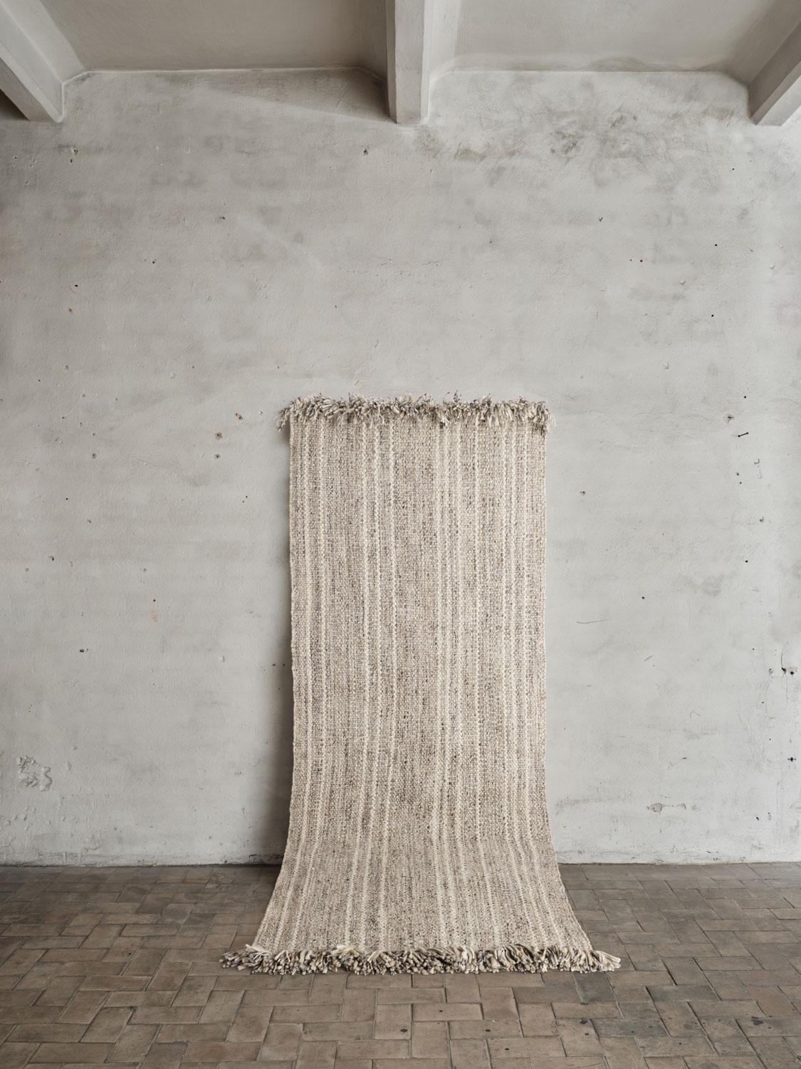 Colonnade no.07 Rug by Cappelen Dimyr
Dimensions: D 100 x H 240 cm
Materials: 100% Wool 

Colonnade no.07 is a hand-woven wool rug designed for narrow  spaces.  no.07 has a mid beige melange foundation with a soft sandy shaded stripe, creating a