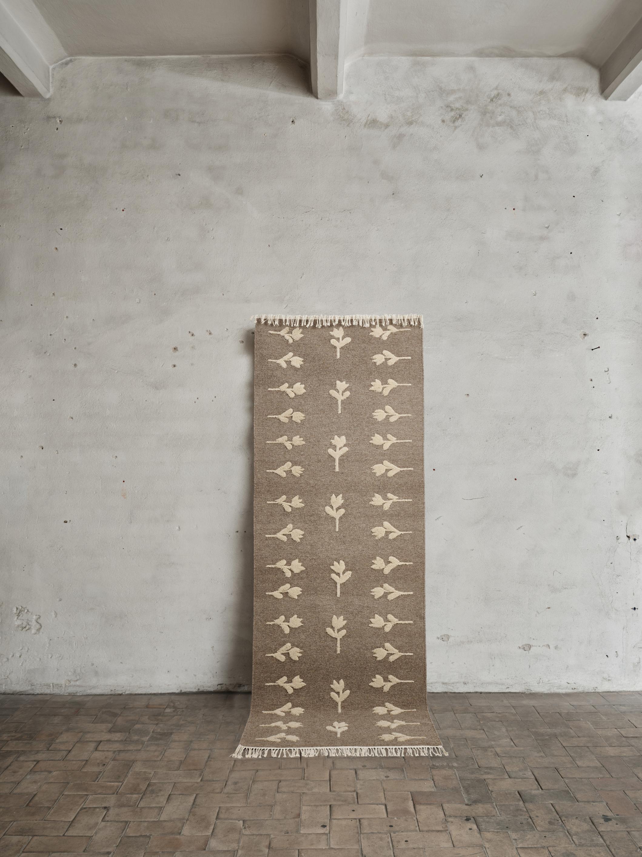 Colonnade no.09 Rug by Cappelen Dimyr
Dimensions: D 85 x H 240 cm
Materials: 85% Wool, 15% cotton

Colonnade no.09 & Rug no.18 is a grey-brown flat-woven rug with light beige hand-knotted floral pattern which gives a slightly high-and low effect,