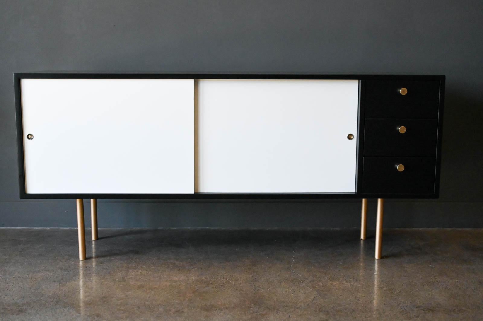 Color Block Credenza by Harvey Probber, ca. 1960.  Original Harvey Probber sliding door credenza newly refinished with color block white and black lacquer.  Original brass hardware on drawers.  Brass toned legs.  This beautiful piece has adjustable