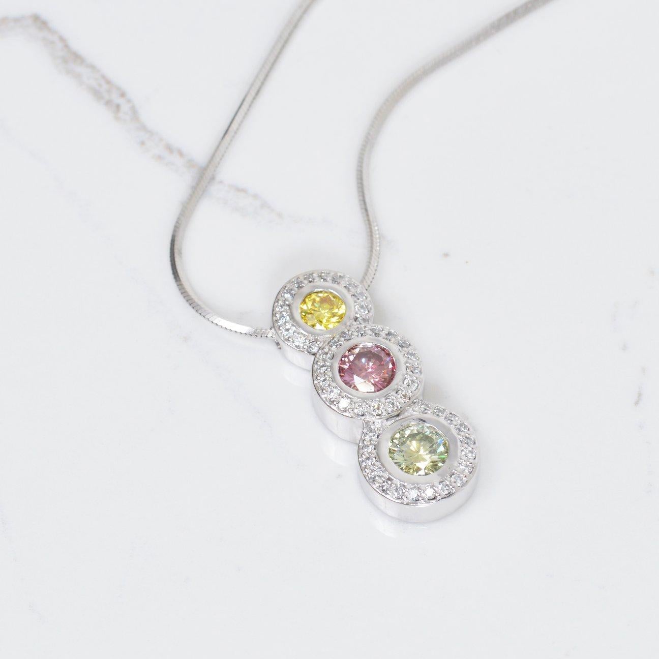 This diamond pendant necklace is truly eye catching! These color enhanced diamonds are absolutlely beautiful. The yellow diamond is .25 carats, purple diamond is .50 carats, and the green diamond is .52 carats. Surrounding these stones is .50 carats