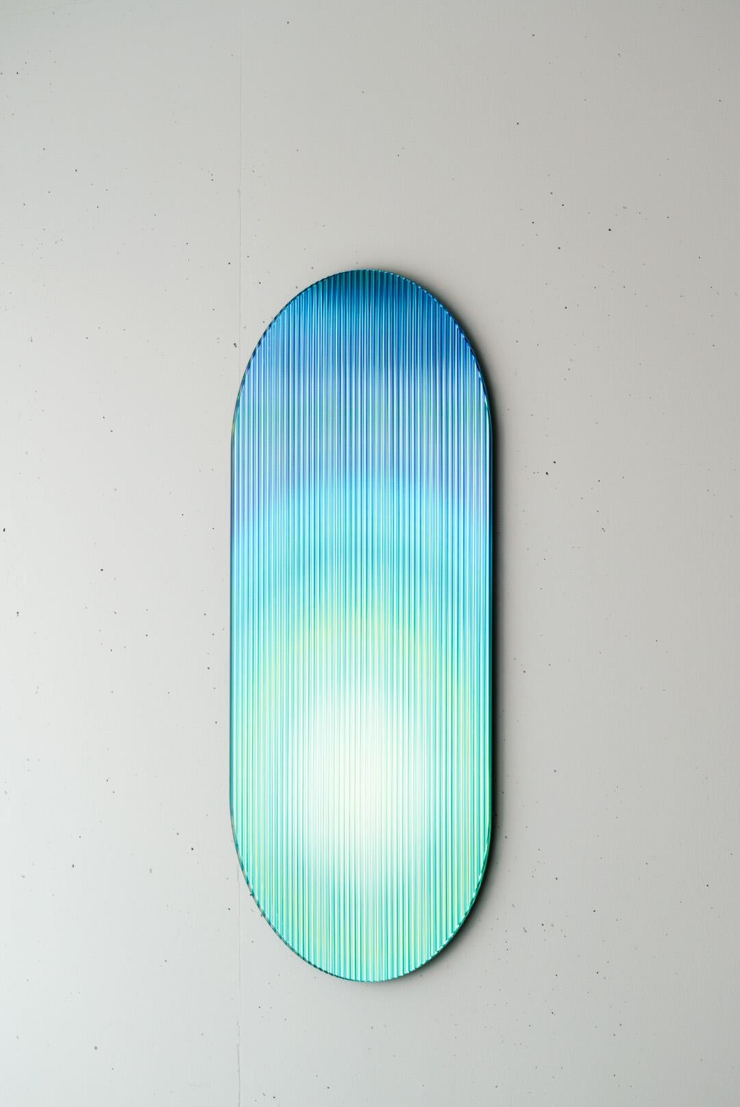 Le panneau de verre réfléchissant, coloré et ondulé - conçu pour ajouter une palette de couleurs aux espaces - reflète la lumière dans les espaces et ajoute du mouvement et de la couleur tout en créant des reflets abstraits. La pièce disperse la