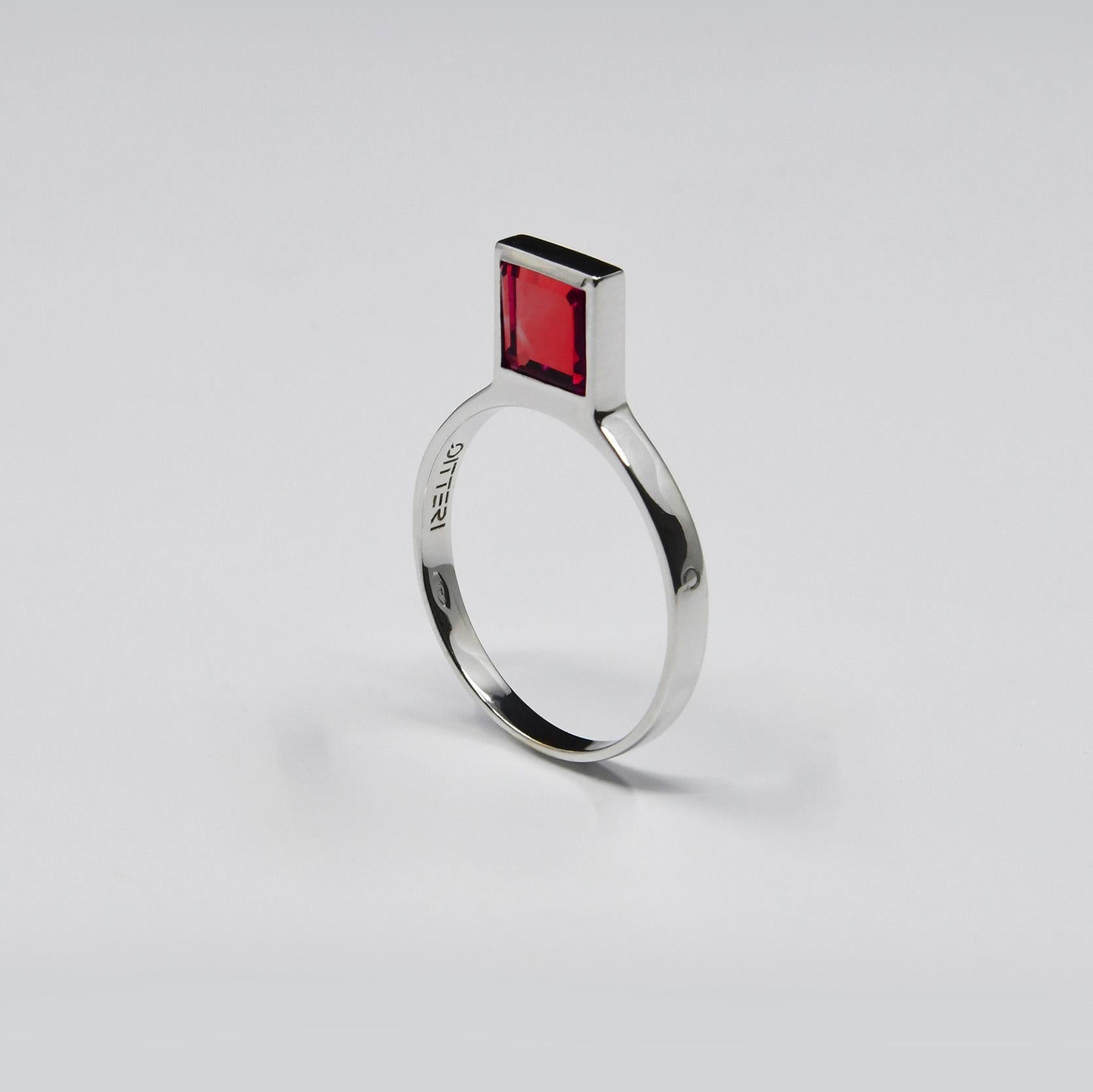 This innovative and contemporary ring, with its unique silhouette, was conceived by designer Michel Tortel for QITTERI. It features a major innovation: a new gem cut in a minimalist square shape in a vertical position. In this model, the garnet is