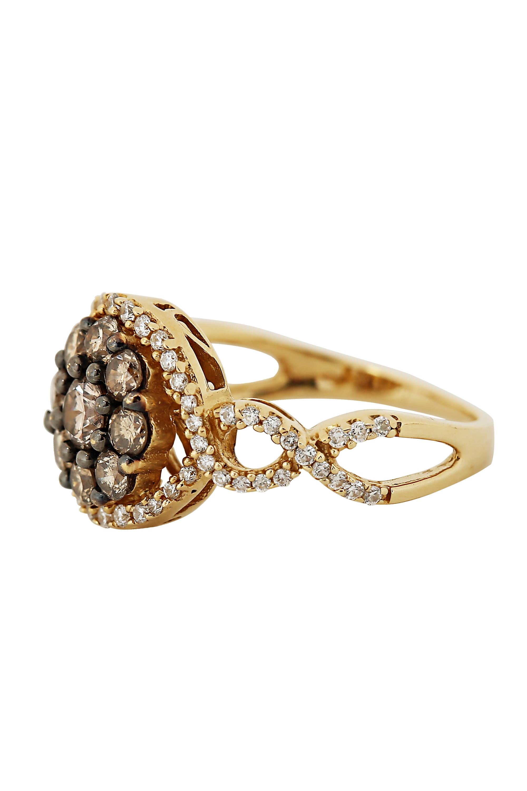 This romantic ring features a center cluster of natural cognac colored diamonds of approximately .70 carats enhanced by blackened gold prongs and a framing of white pave diamonds terminating in graceful openwork shoulders. The ring is fabricated in