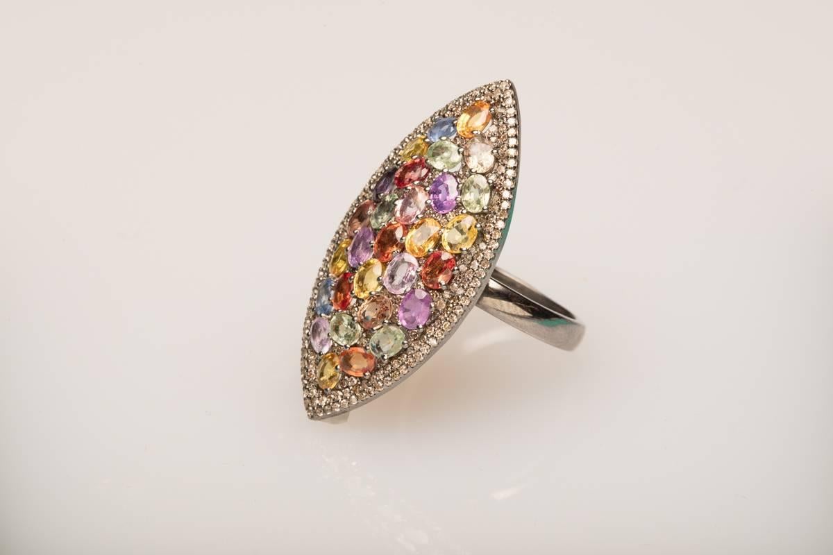 A marquise-shaped ring with a mosaic of faceted, colored oval sapphires of exceptional brilliance, bordered in a double row of pave` set diamonds.  Set in an oxidized sterling silver.  Carat weight of diamonds is 1.15; sapphires are 6.38.  Ring size