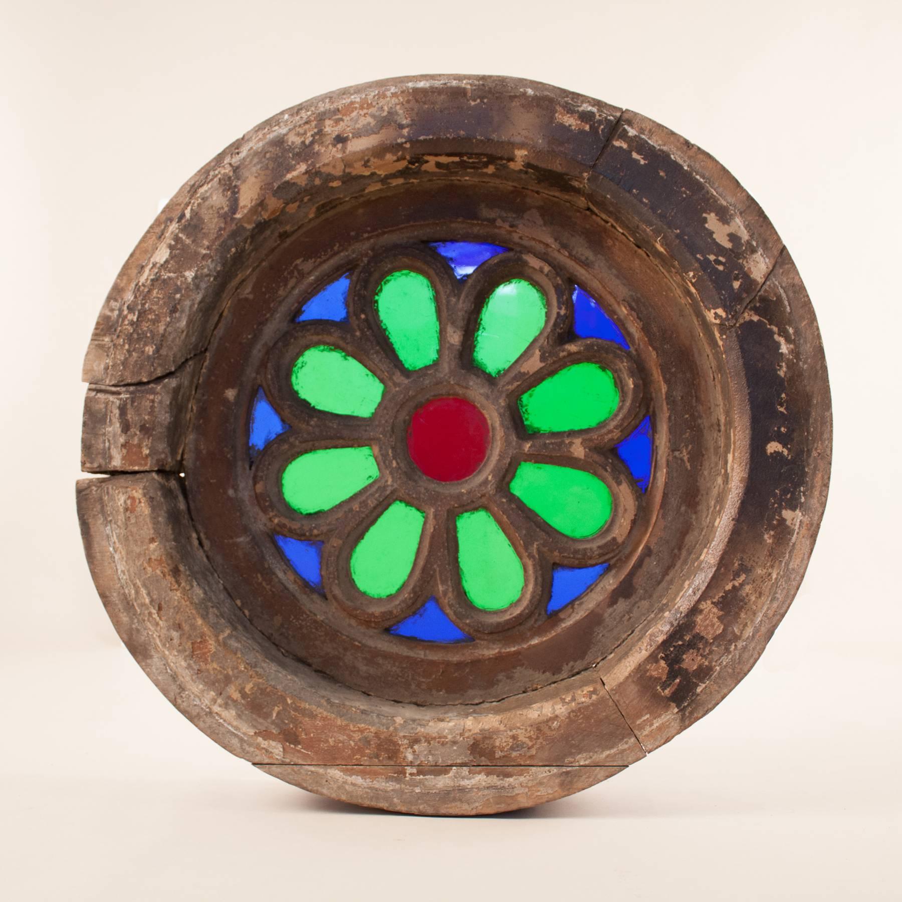 A rare and beautiful piece of colonial history, this circular window is fabricated from vibrant blue, green and red translucent glass set in a thick, three-piece teak wood frame. Likely salvaged from a Goa heritage home, this circa 1900 window is in