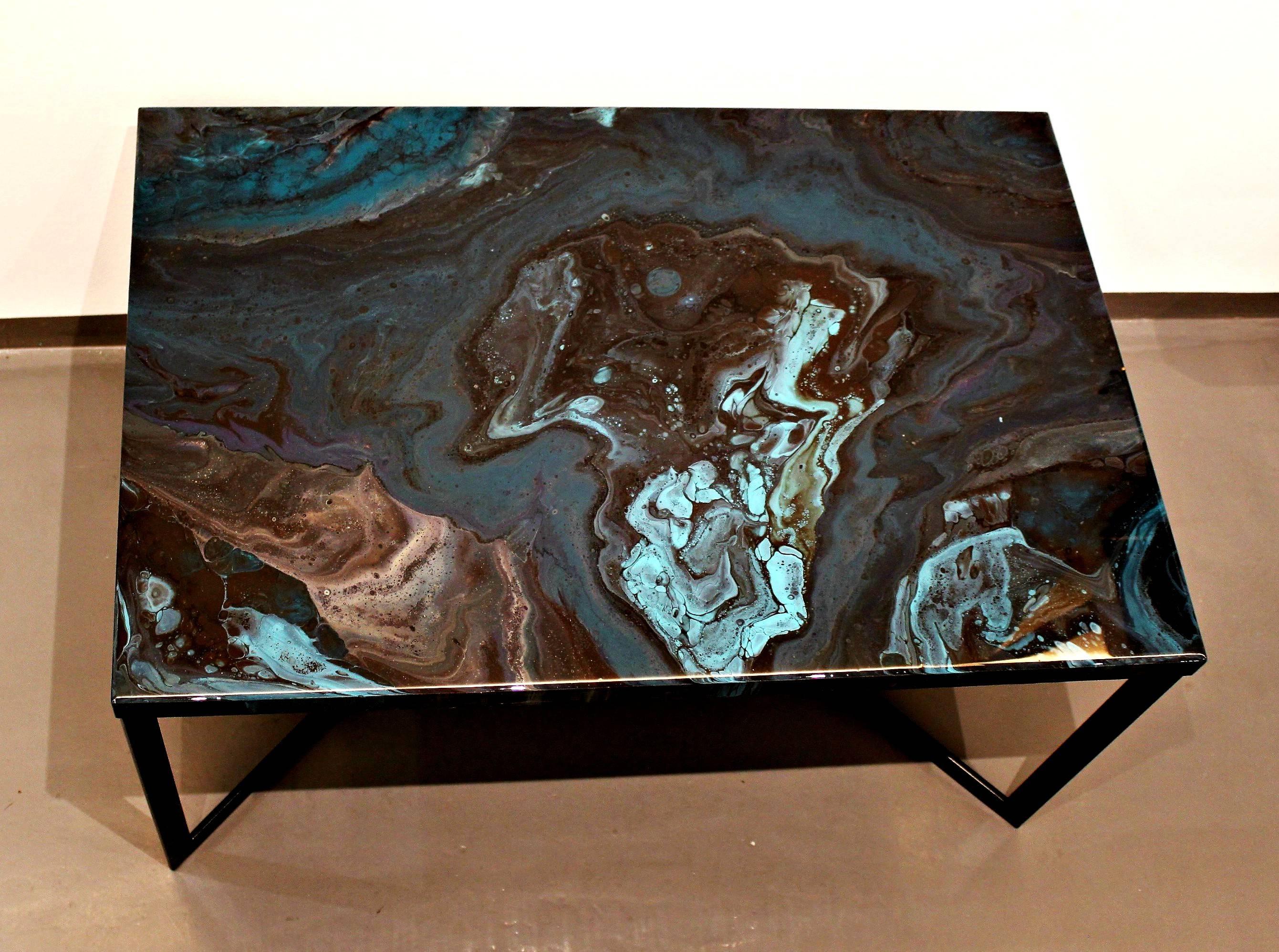 Outstanding resin coffee table that consists a piece of art. The tabletop is hand painted with a unique technique that combines pigments, inks and layers of resin on wood. Inspired by nature, rivers of teal with lighter and darker hues, supplemented