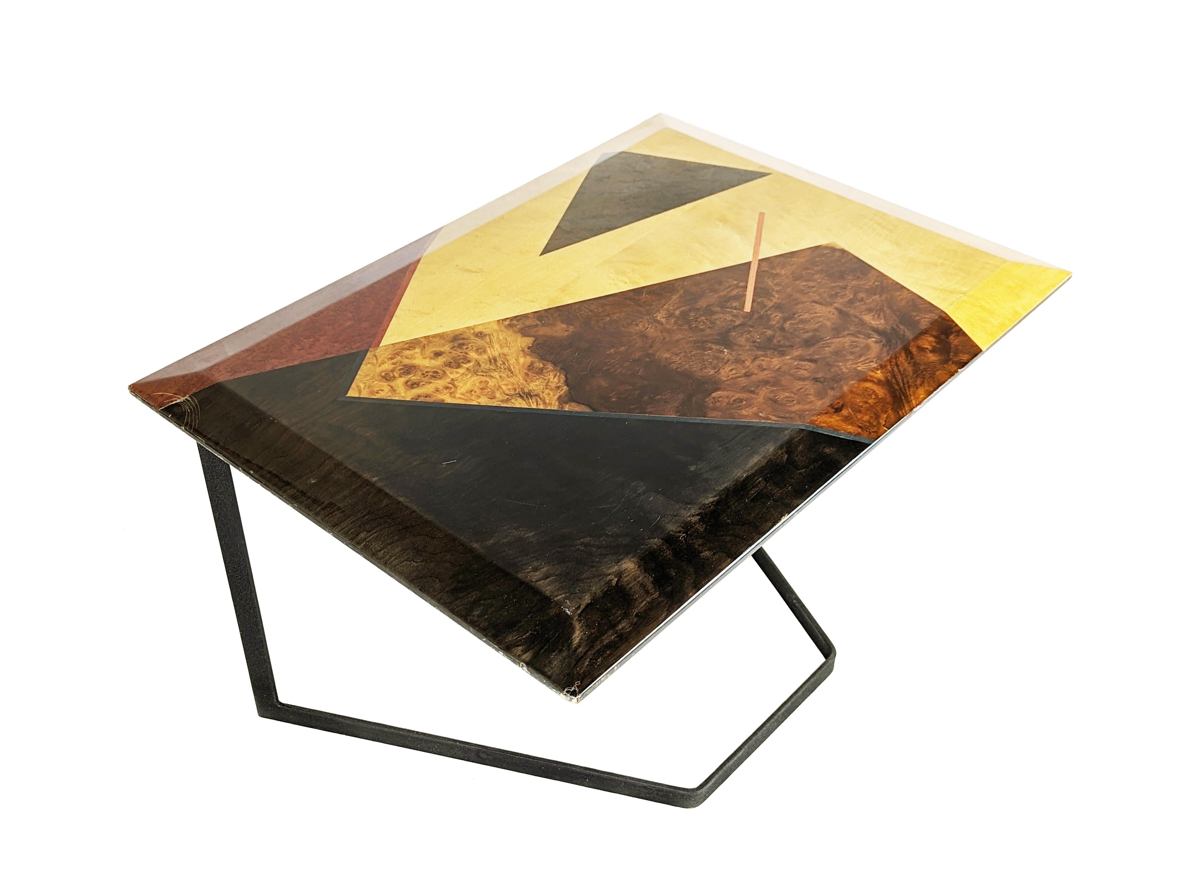 Rare table basse avec plateau en bois avec incrustations géométriques colorées et base en métal peint craquelé. Le plateau, biseauté sur 4 côtés, est constitué d'un design géométrique avec des incrustations de racines teintées à l'aniline.La plaque