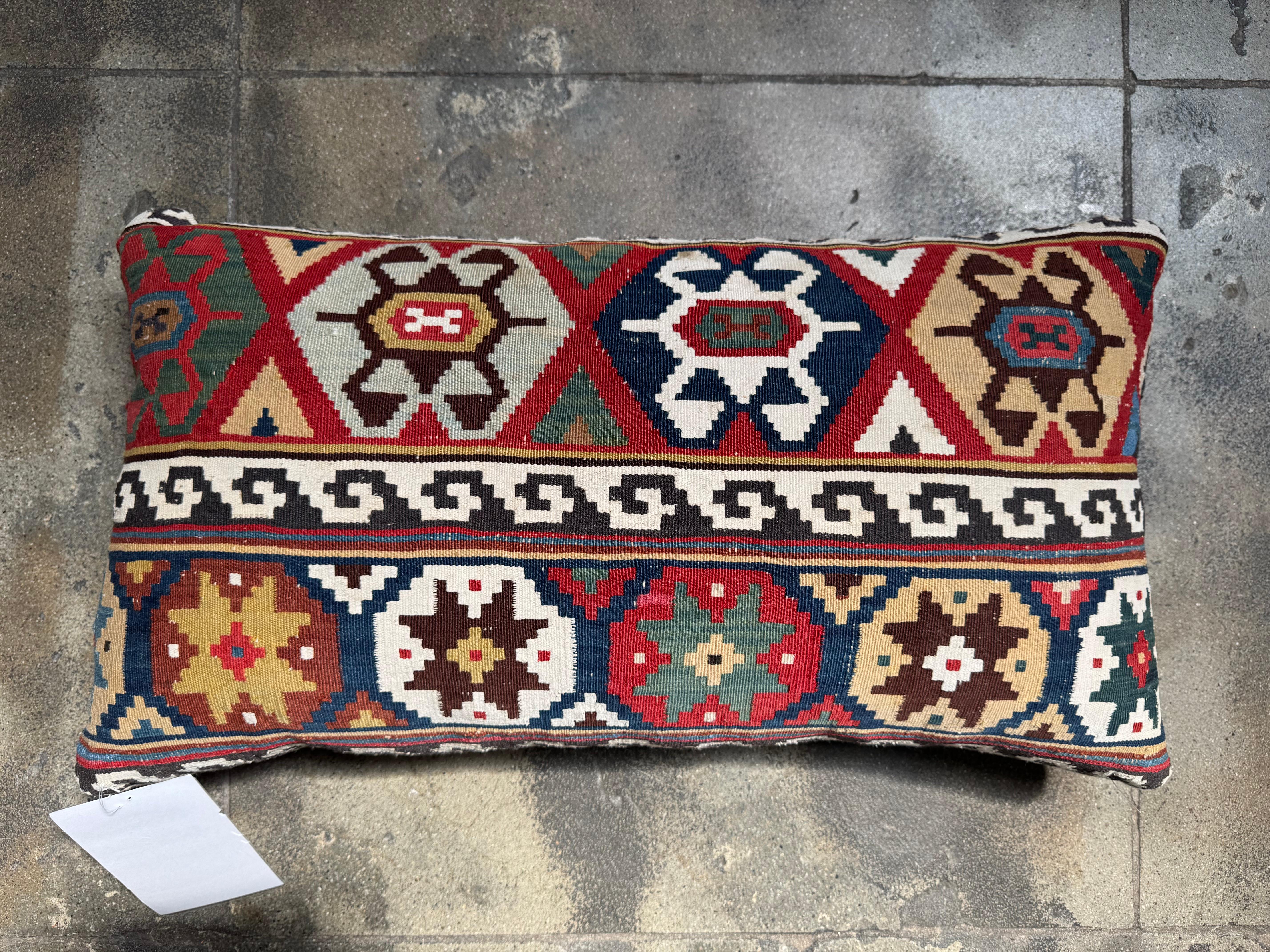 A vibrant celebration of antique textile tradition, this 19th century Caucasian kilim lumbar pillow showcases masterful craftsmanship and bold geometric design. The handwoven wool cover features a dazzling array of star and medallion motifs,