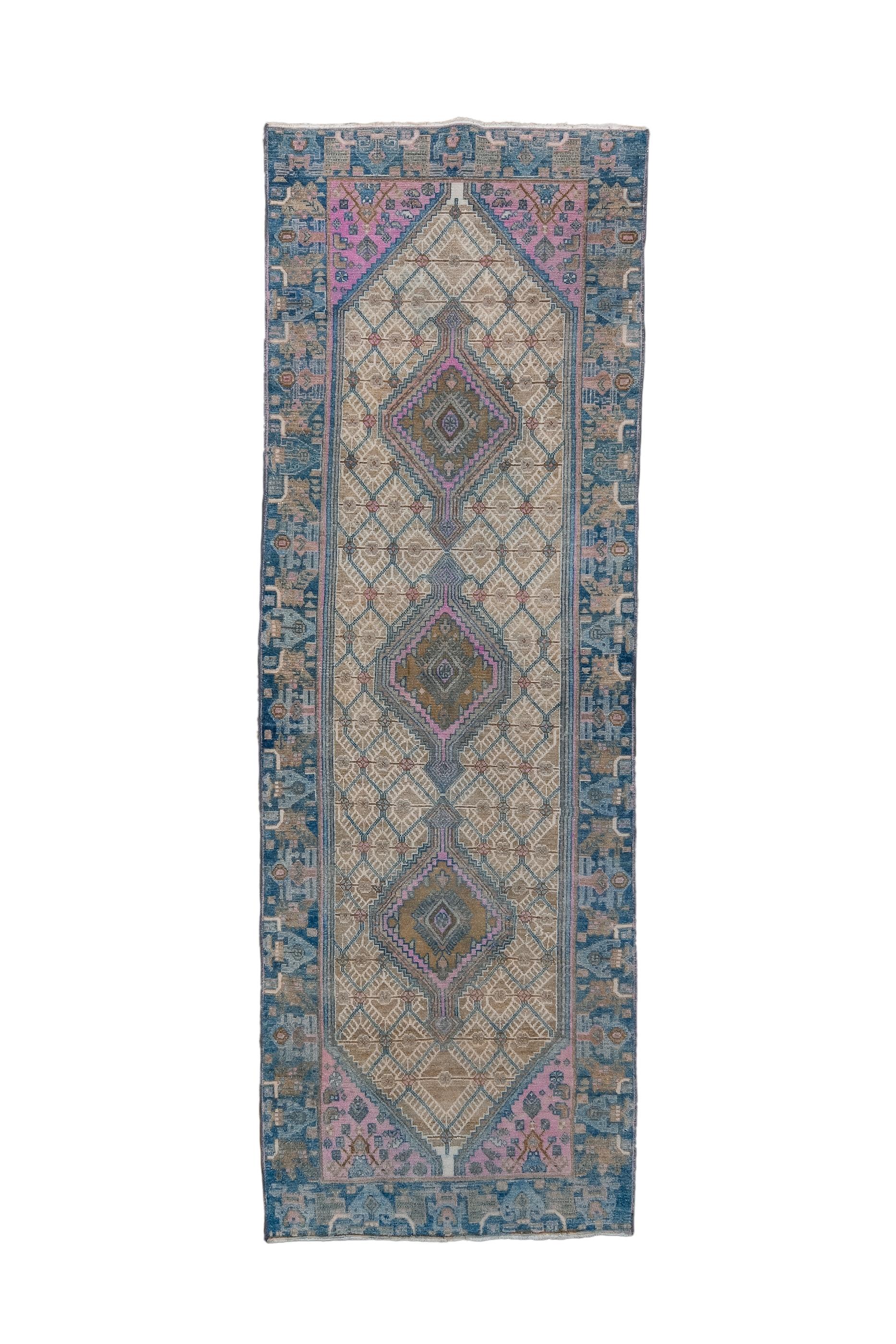 Ce kellegi (long tapis) coloré présente un sous-champ en pointe densément garni de diamants frangés uniformes et supportant une série tripartite de diamants imbriqués et dentelés. Le champ bleu ciel est étroit sur les côtés et s'élargit pour former