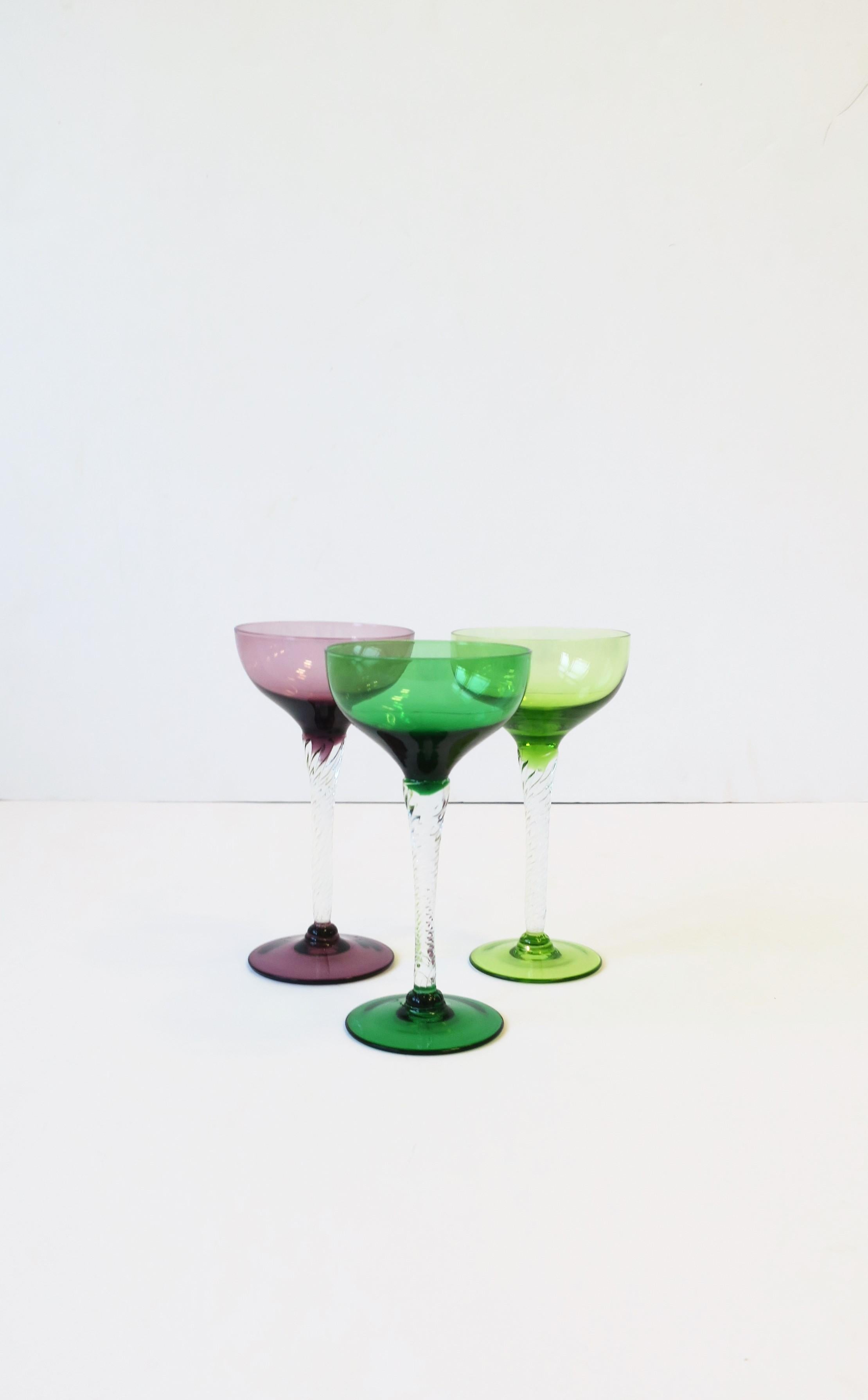 Un magnifique ensemble de trois (3) verres à cocktail ou à champagne en verre soufflé vintage, vert émeraude, vert chartreuse et violet/aubergine, avec une tige torsadée transparente, vers la fin du 20e siècle, Europe, peut-être Italie. Un ensemble