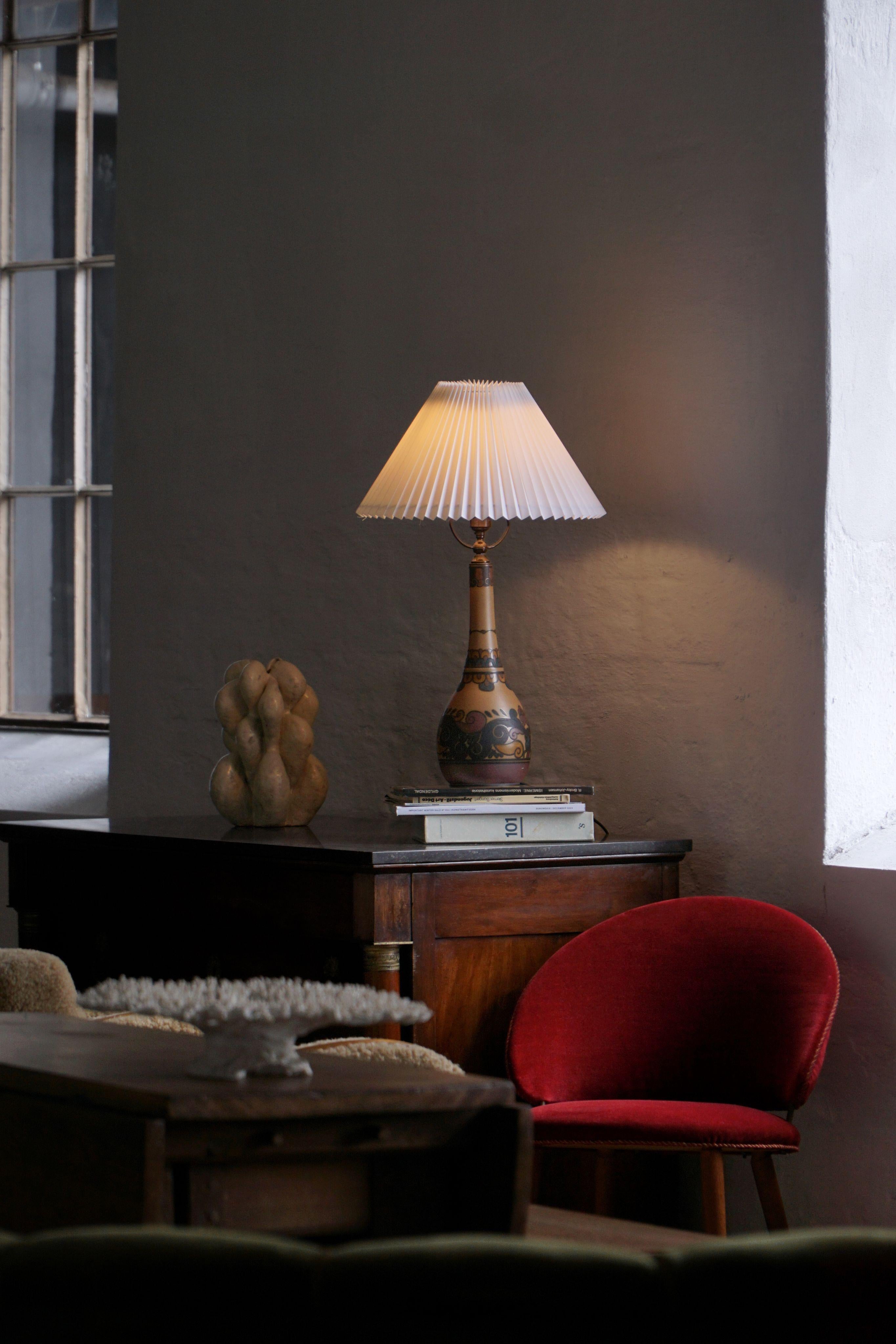 Una lampada da tavolo in terracotta finemente decorata a mano dallo stimato studio di ceramica I.L.A. Studio sull'isola di Bornholm, in Danimarca. Risalente agli inizi del XX secolo, questo pezzo esemplifica la raffinata abilità artigianale e la