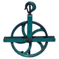 Vintage Colorful dark blue and teal large industrial cast iron pulley on a metal base.