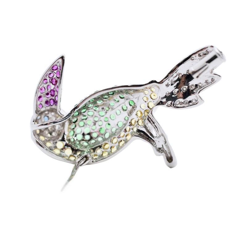 Aston Estate Jewelry Presents:

A cheerful and bright toucan bird pendant in 18 karat white gold. Set throughout with green garnets, red rubies, yellow sapphires, a blue sapphire eye, red rubies, and of course diamonds. Total diamond weight 0.30ct