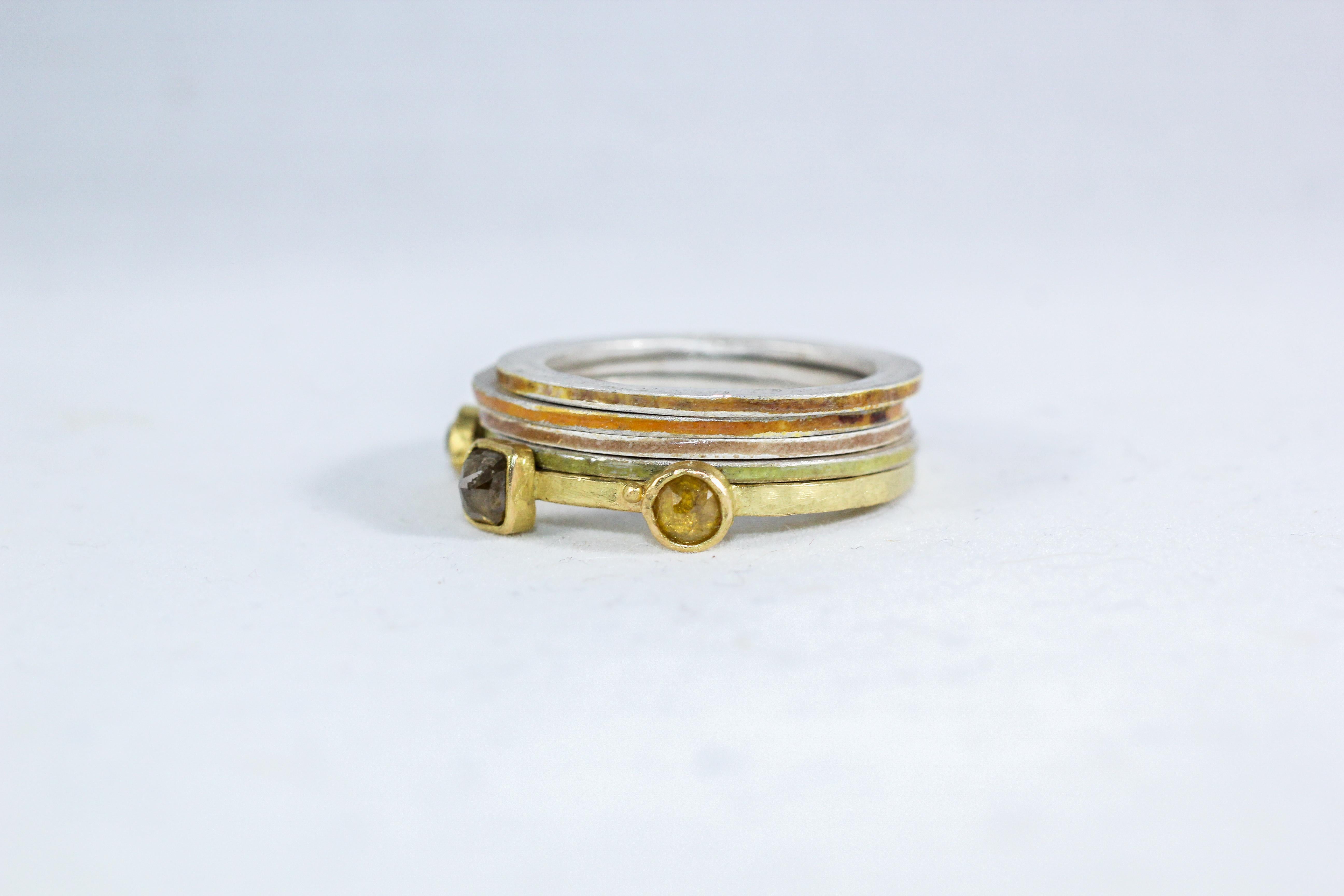 This fashion cocktail stack of bands combines our 18k recycled gold three-stone diamond ring and 4 enameled fine silver rings. Three fancy-colored diamonds are set in bezels. The rich yellow of high-carat gold is complemented by the subtle pastel