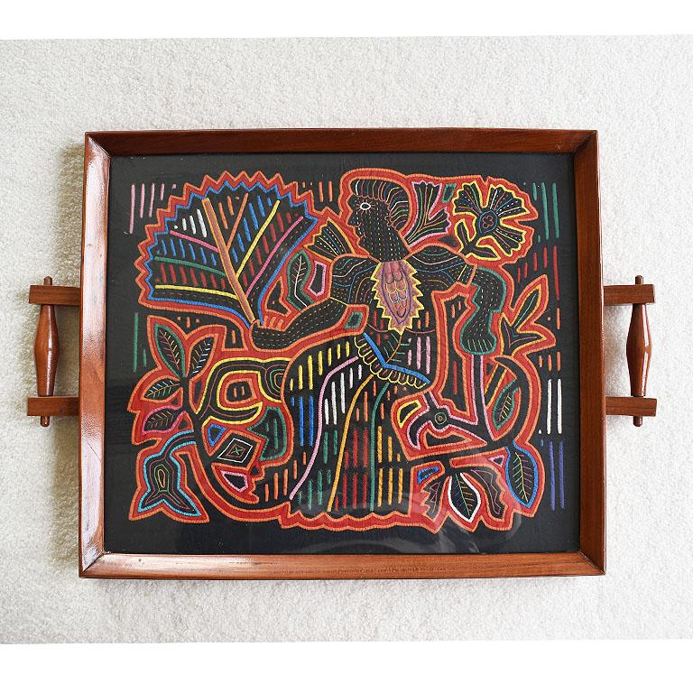 Ein wunderschönes Serviertablett aus Holz mit einem handgestickten, figuralen Motiv aus Textil unter Glas. Dieses farbenfrohe Serviertablett macht sich hervorragend an der Wand oder zum Servieren von Getränken. Der Stoff ist mit einer Reihe von