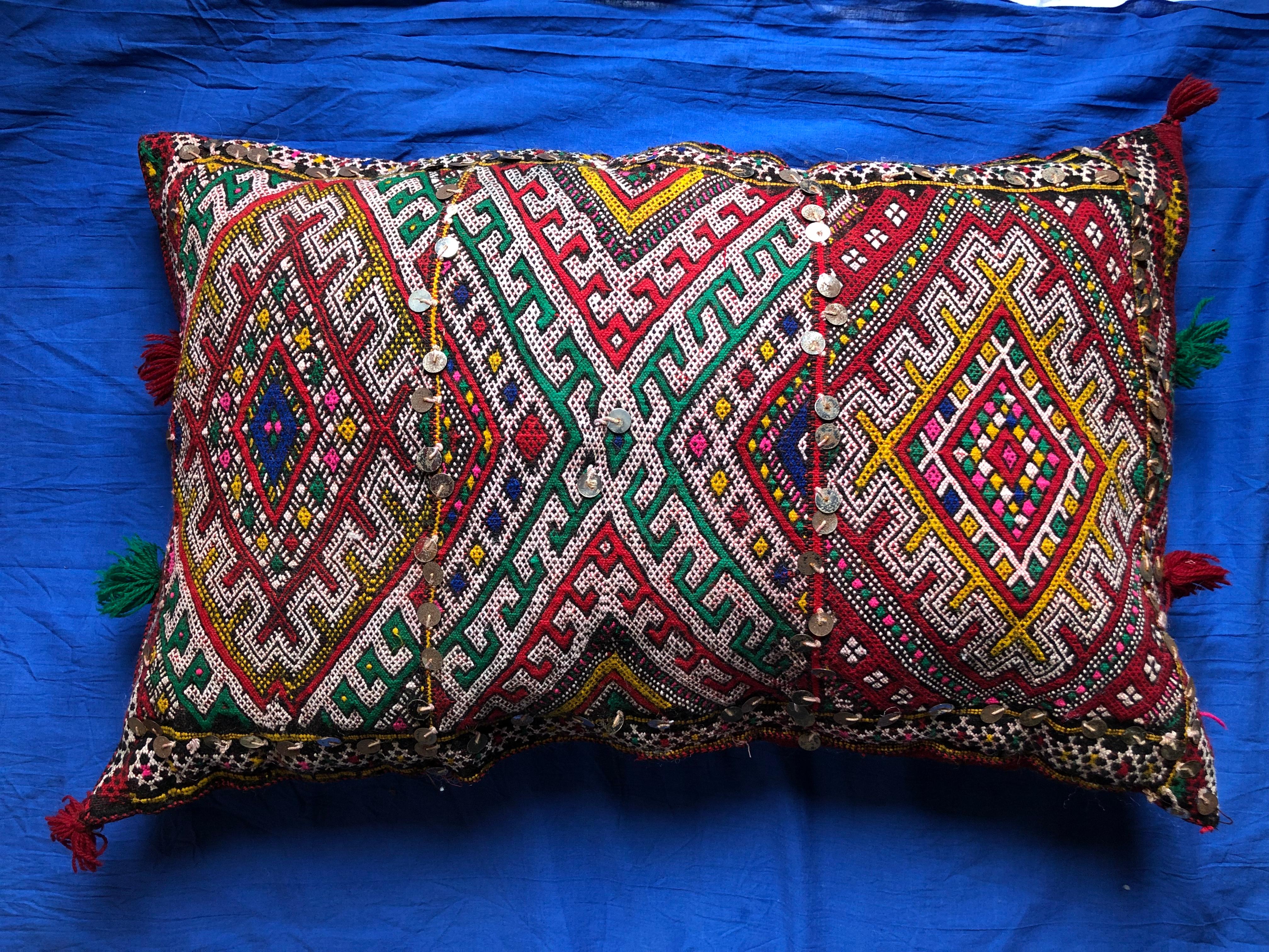This vibrant, colorful handmade pillow adds an exotic bohemian feel to any room. Decorated with geometric designs that mimic Berber tribal tattoos, as well as other symbolic imagery like the evil eye. Each pillow is one-of-a-kind, handwoven by