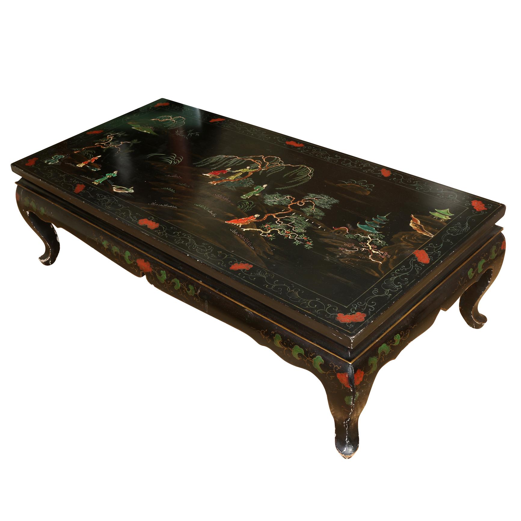 Une table basse vintage de style asiatique, peinte à la main et colorée, représentant des personnages et des arbres dans des paysages. La table est rectangulaire avec des pieds cabriole.