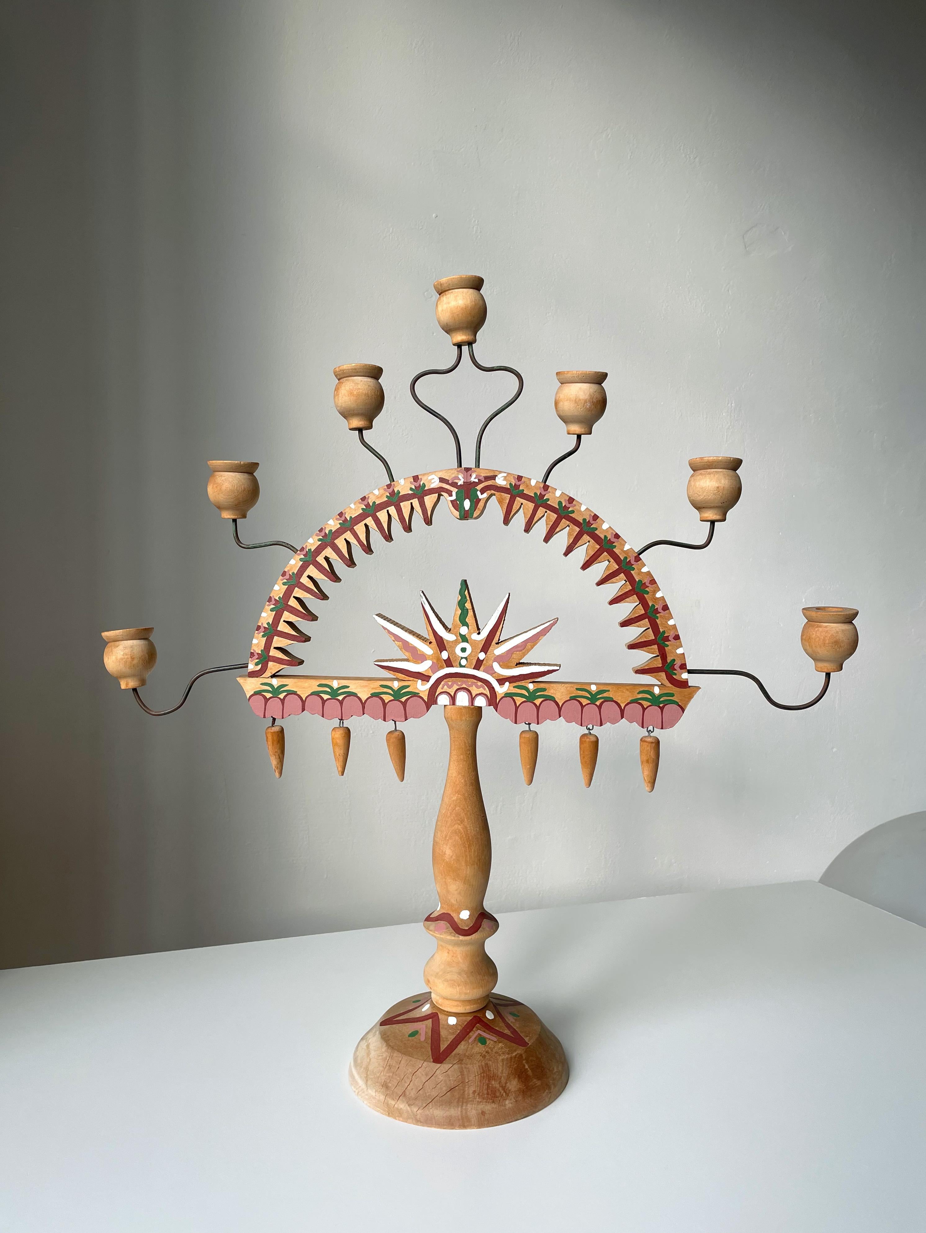 Large folkoristic wooden hand-crafted candelabra with seven arms attached on thin, slightly adjustable metal rods. Handpainted in Nordic folklore style with burgundy, rose, green and white colors in organic, floral and star shaped patterns.