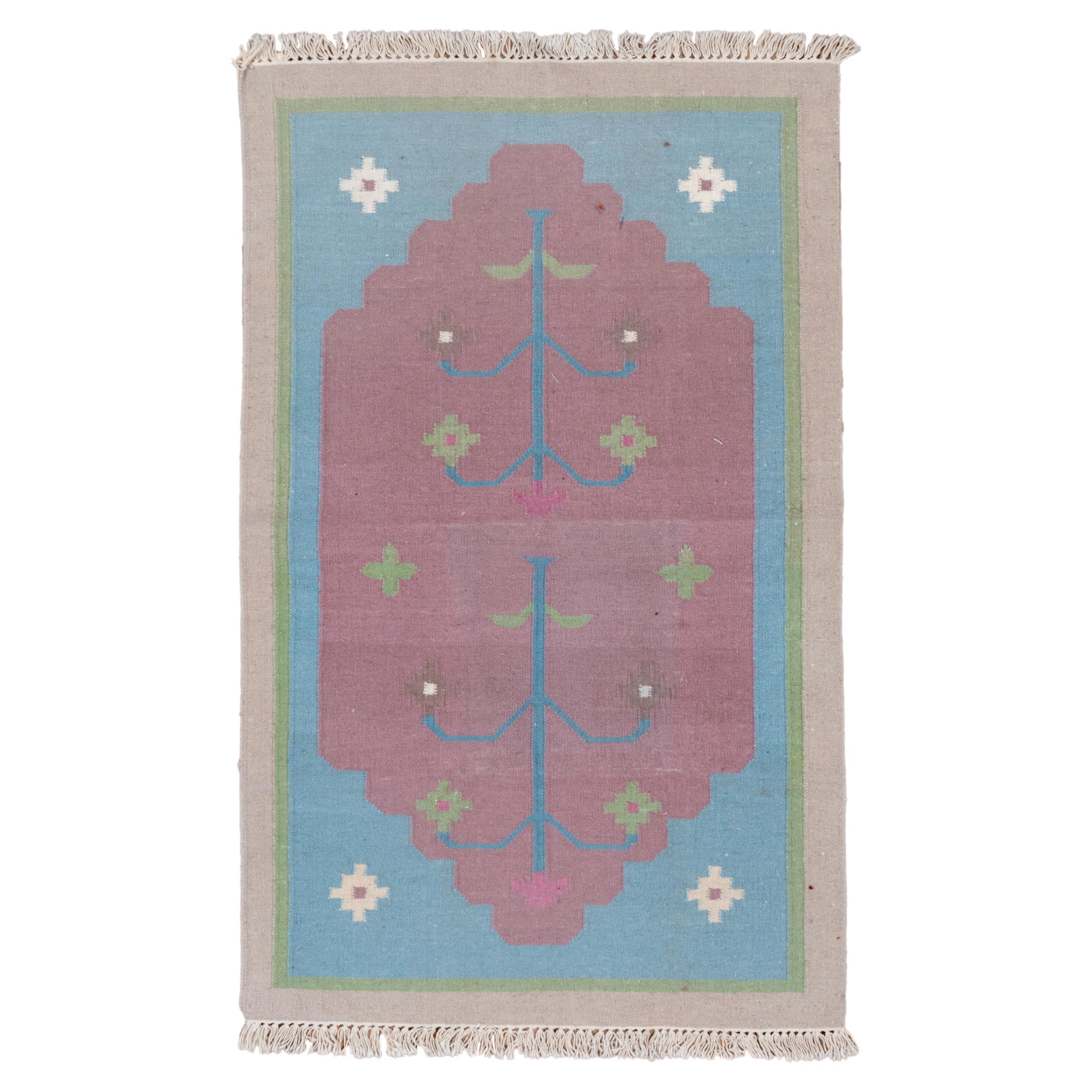 This fairly well-woven, tapestry technique, all-cotton scatter presents a luminous light blue field with off-white stepped cross corner pieces, supporting a partially cusped, abrashed pink sub-field with a central stylized tree, and stepped and
