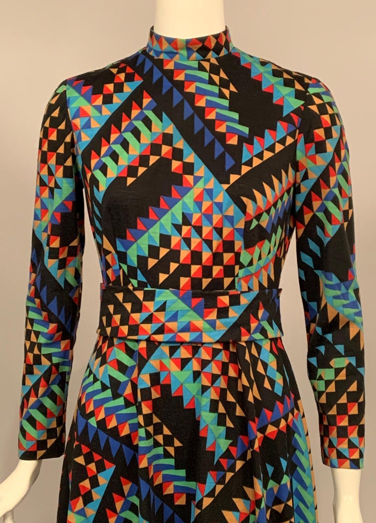 This dress was created by an anonymous designer, but you will be anything but anonymous wearing this fabulously colorful Op Art patterned dress from the late 1960's.   The dress has a high collar, a fitted waistline with a wide self belt, long