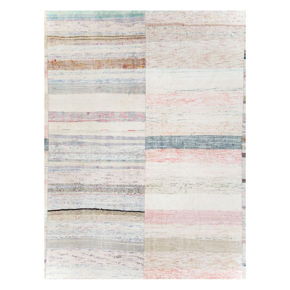 A vintage Turkish flat-weave Kilim room size carpet handmade during the mid-20th century. Predominantly in white with colorful stripes including shades of pink, blue, purple, light green, among other tones, the design is fun and cheerful, and