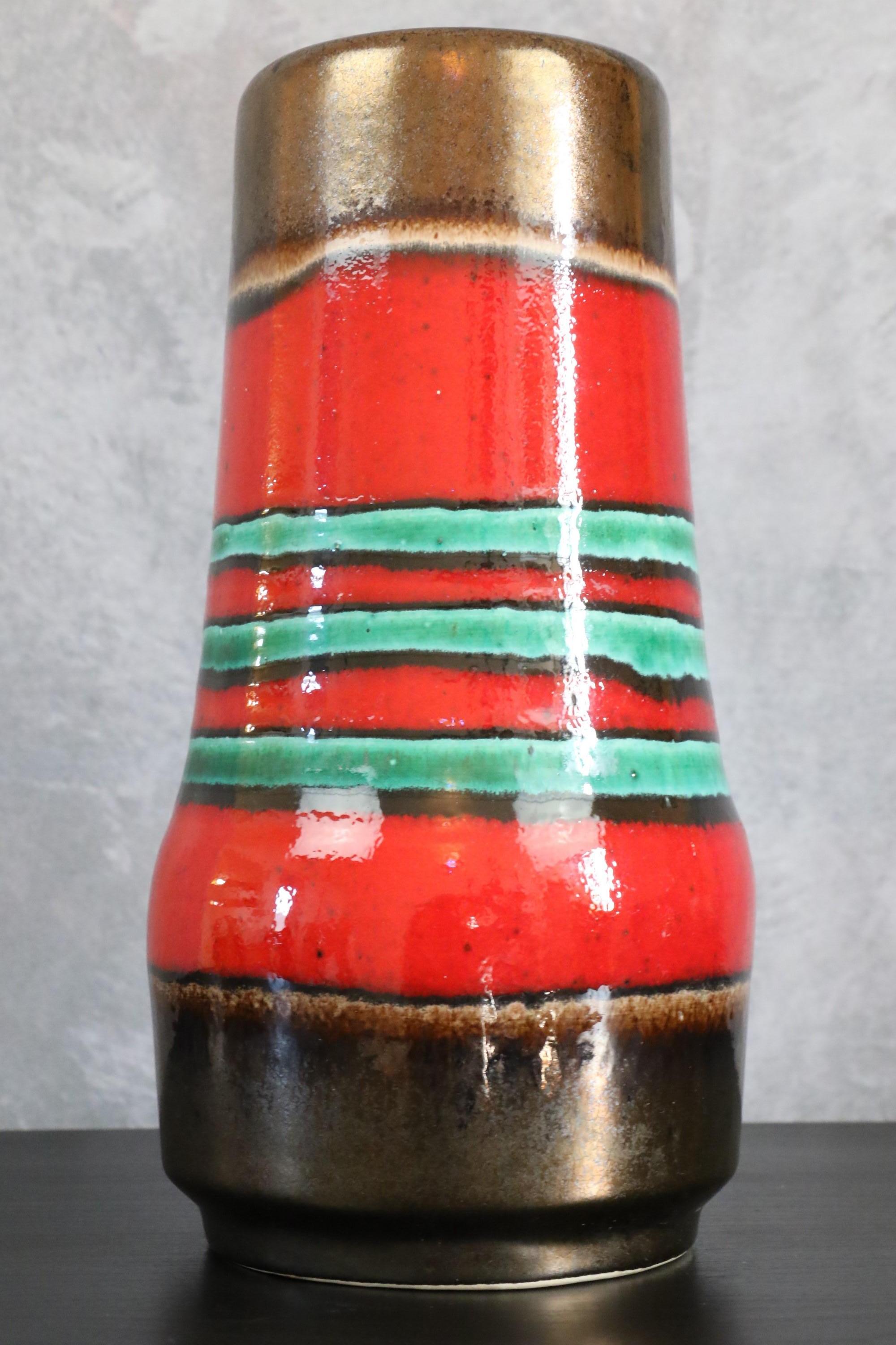 Colorful Mid-Century Modernist from West Germany vase, circa 1970

The enamel is very bright, the red contrasts with the blue stripes giving a lot of character to this piece. The neckline of the vase is worked with a slightly golden and shiny