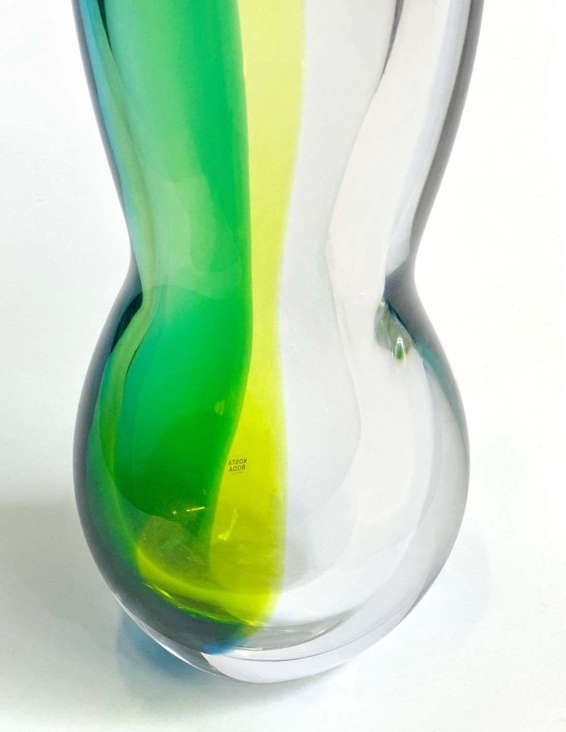 Stunning Italian vase adorned with captivating hues of blue, green, and yellow, crafted with Murano glass by Kosta Boda. The vibrant color palette of blue, green, and yellow immediately catches the eye, evoking a sense of energy and vitality. The