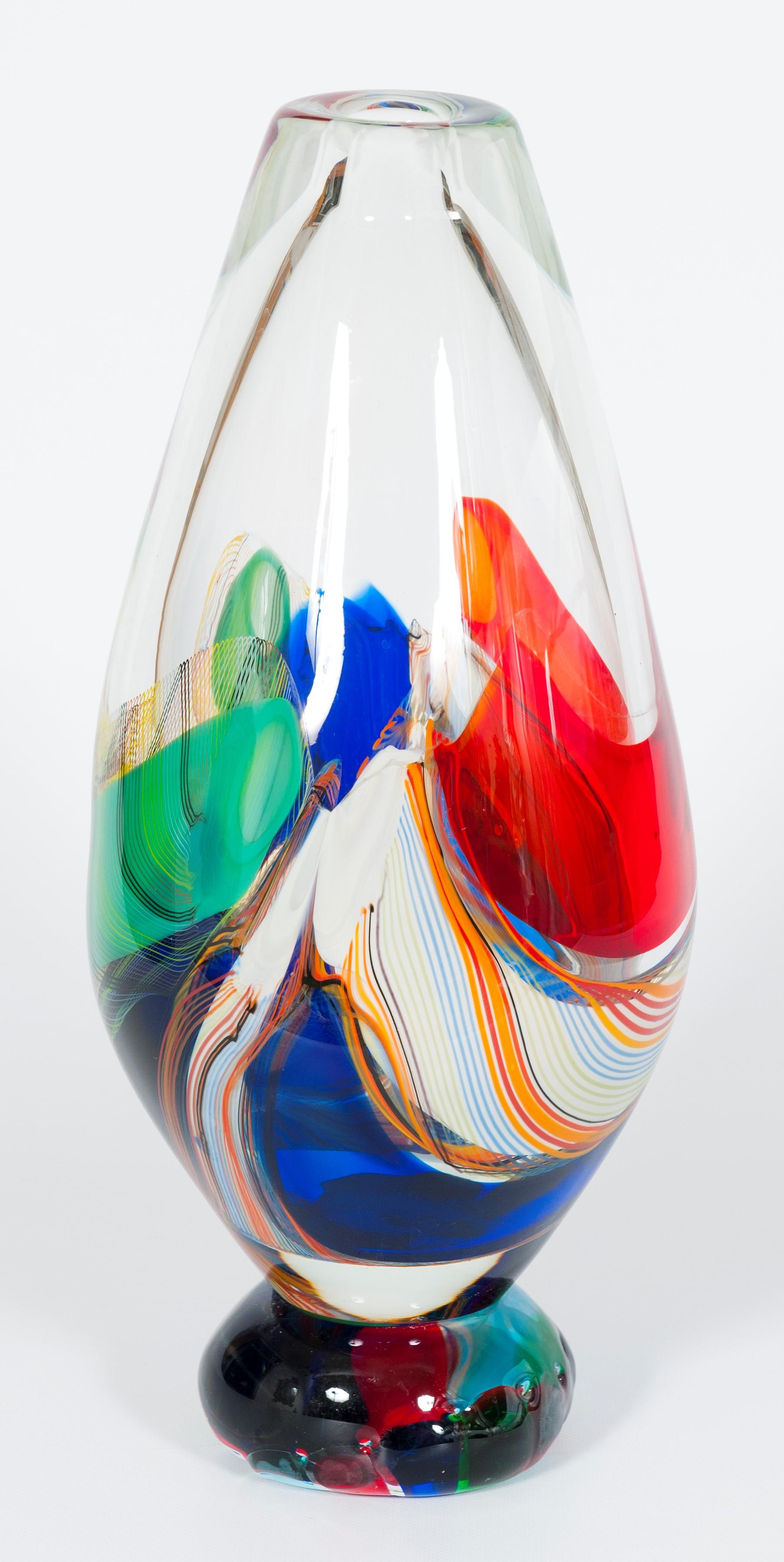 Vaso in vetro di Murano colorato di Romano Donà Venezia anni '80.
Questo raro vaso artistico si distingue per i suoi colori energici, ottenuti con diverse tecniche di lavorazione. Tutti i colori sono immersi in vetro soffiato trasparente; alcuni