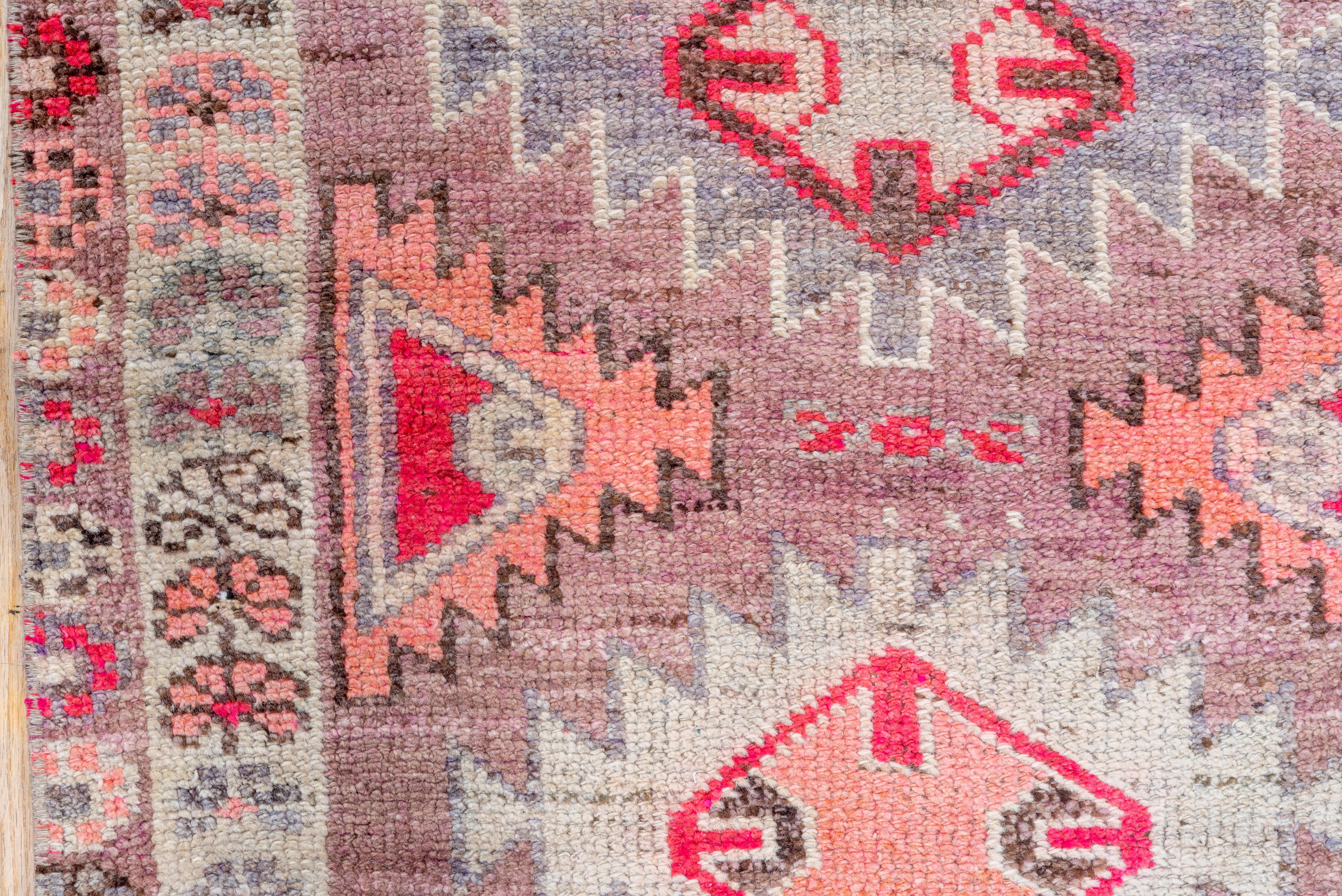 Ten lozenge shaped serrated ashiks parade up the abrashed mauve purple field with en suite side filler triangles. Red, ivory details. Baby blue main border with ascending, detached fan palmettes.