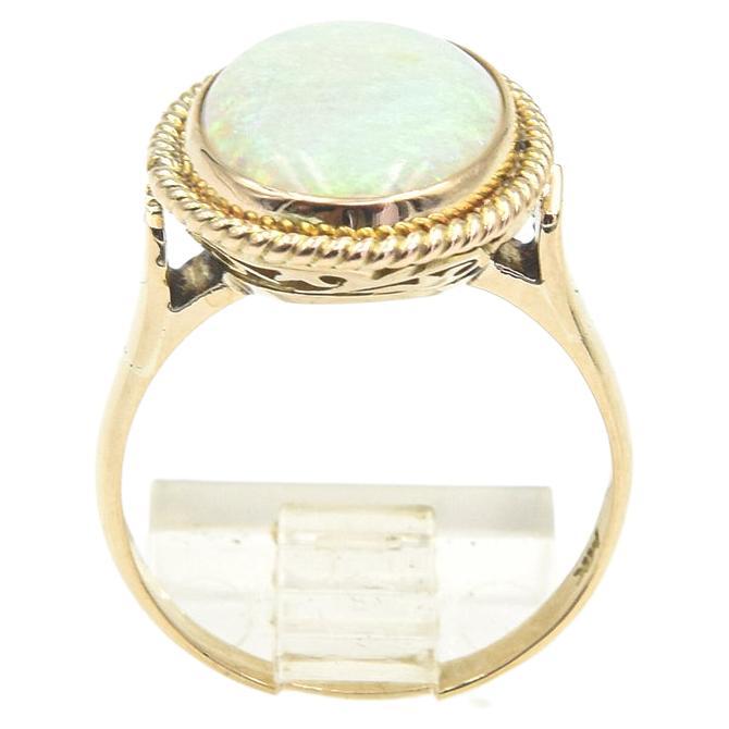 Beautiful oval opal with blue, green, red and yellow color play mounted in a simple twisted rope frame.  The ring is 14k yellow gold.  US ring size 8.25.  The ring measures .62