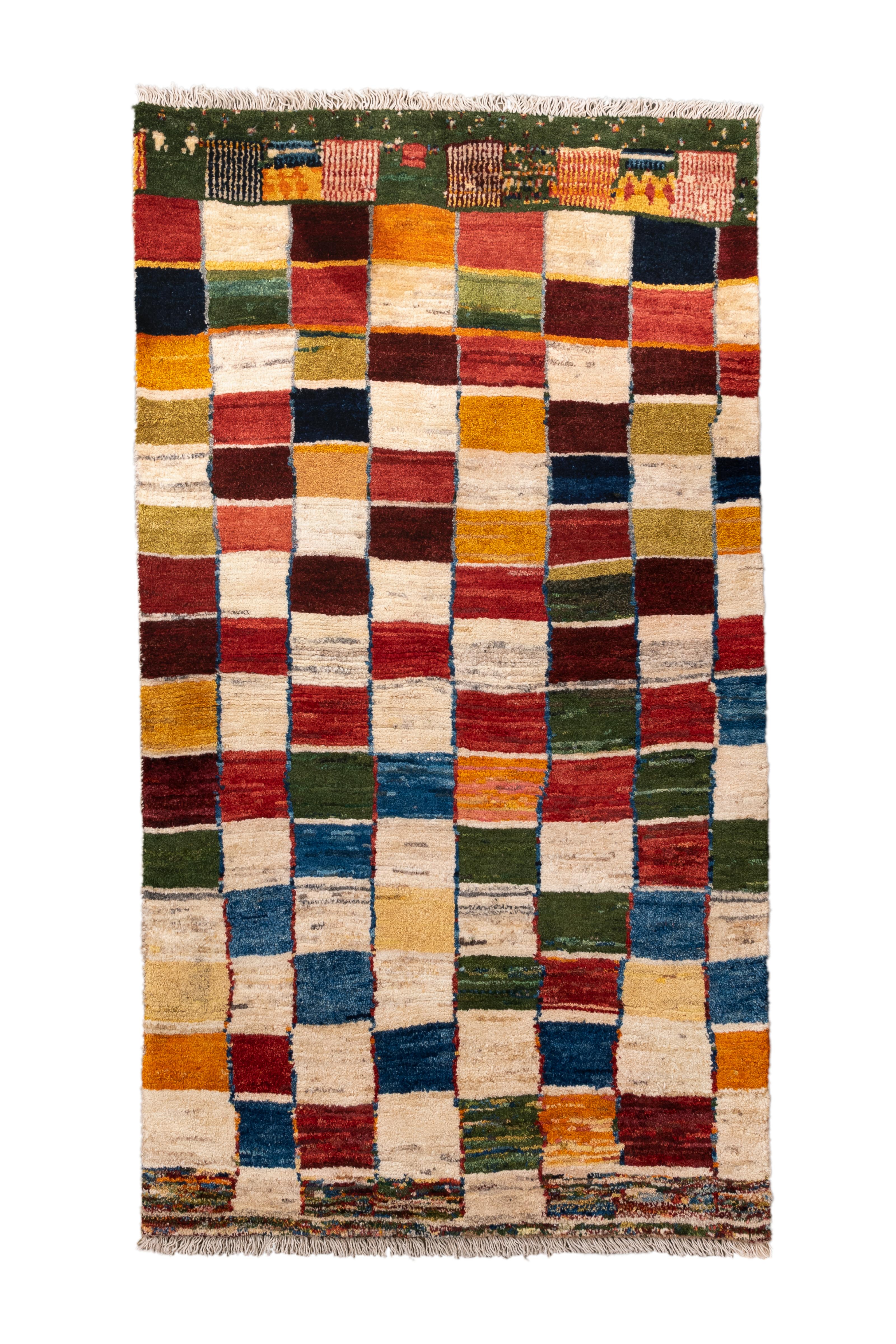  Dieser schillernde und lebendige Gabbeh-Teppich im Vintage-Stil zeigt ein abstraktes Schachbrettmuster mit unterschiedlich großen Rechtecken in satten Juwelentönen: Karneolrot, Ocker, Marineblau, Jägergrün und Elfenbein. Vor allem die obere und