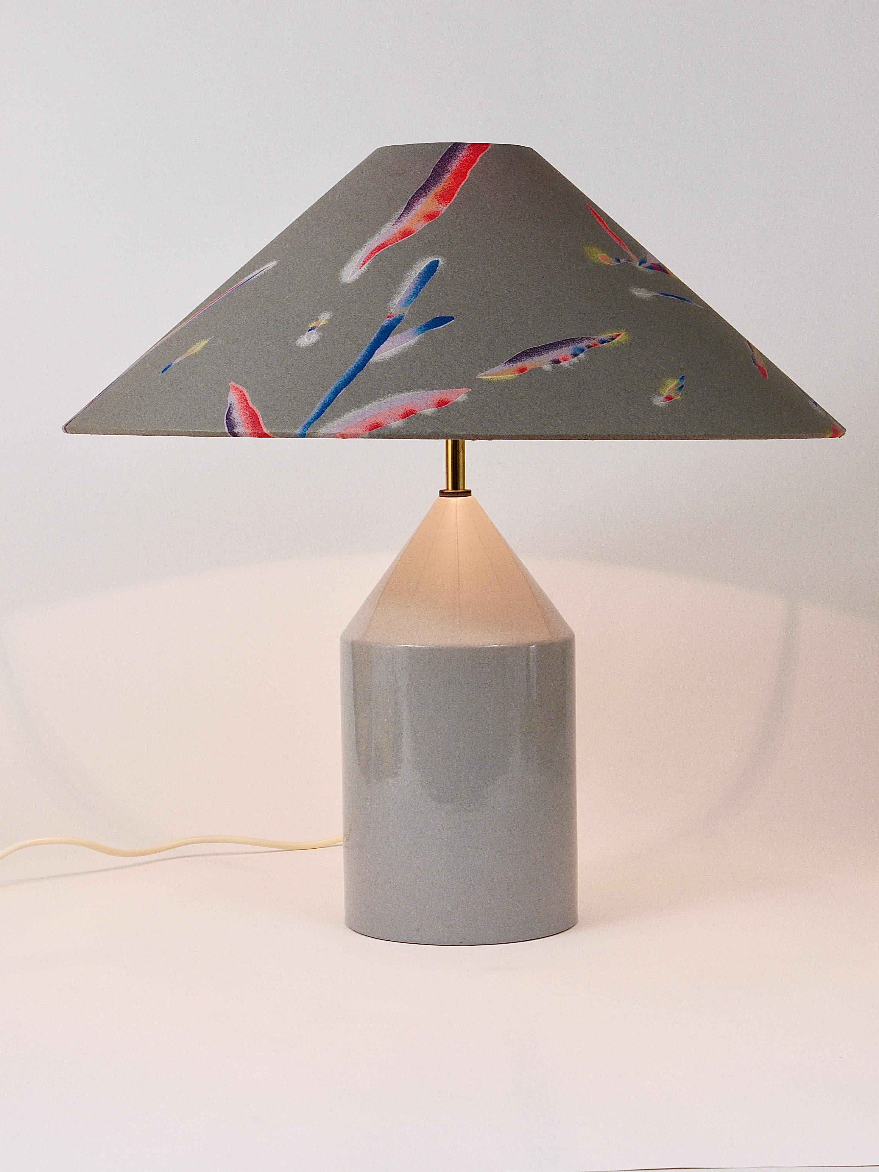 A beautiful Italian postmodern table lamp / side lamp from the 1980s. The lamps base is made of ceramic with a light-grey shiny glaze. It still has its original conical lampshade with an amazing floral and colorful 1980s pattern. In very good
