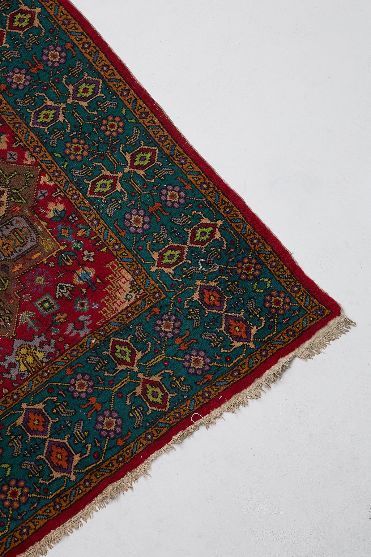 20th century Turkish tribal style carpet featuring geometric patterns in colorful purple, greens, and blues with a red ground. Adorned with multiple hieroglyph symbols and shapes. Vibrant colors with losses as seen in photos.