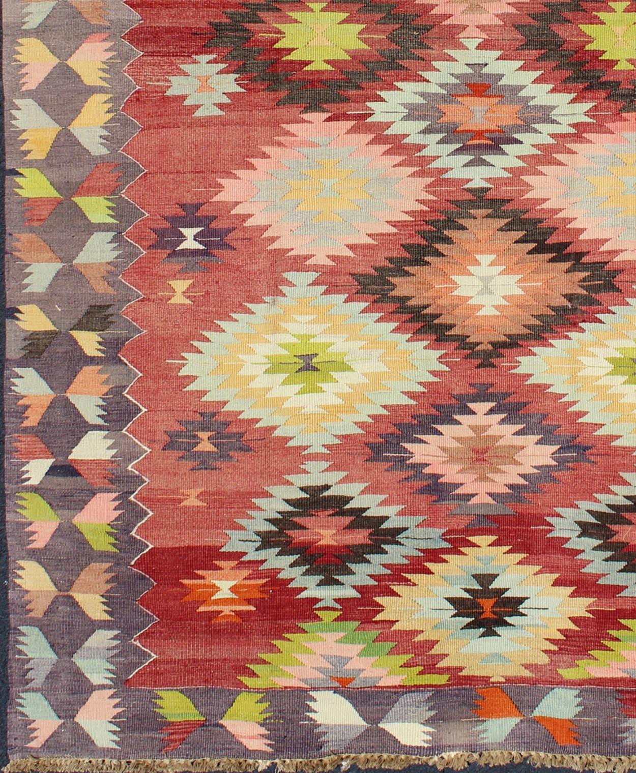 Colorful Turkish Kilim Carpet with Geometric Design.
This beautiful vintage Turkish Kilim from the 1960s features bold and colorful geometric designs throughout both its centre field and border. Colors include red, lime green, salmon, ivory, grey,