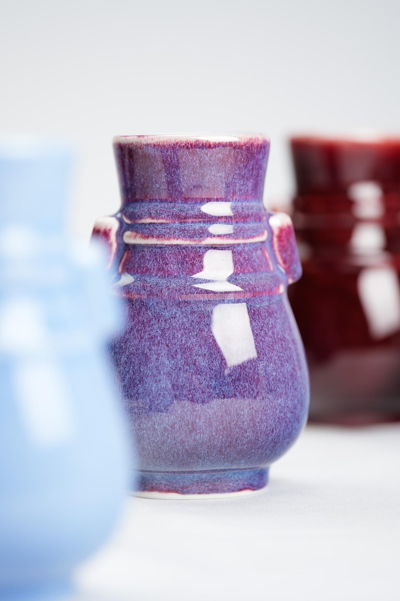 Shi Jie Weng interpretiert die klassische Vase mit zwei Henkeln neu und präsentiert sie in einem charmanten Miniaturformat. Mit seiner charakteristischen Palette von elf monochromen Glasuren verwandelt er die traditionell feierliche Silhouette in