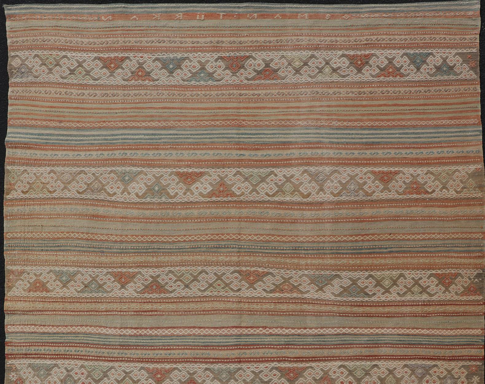 Geometric stripe design Kilim rug in multi-colors in muted tones, rug EN-179892, country of origin / type: Turkey / Kilim, circa 1950

Measures: 6'1 x 8'9

This vintage Kilim displays an array of designs, including a striped pattern and small