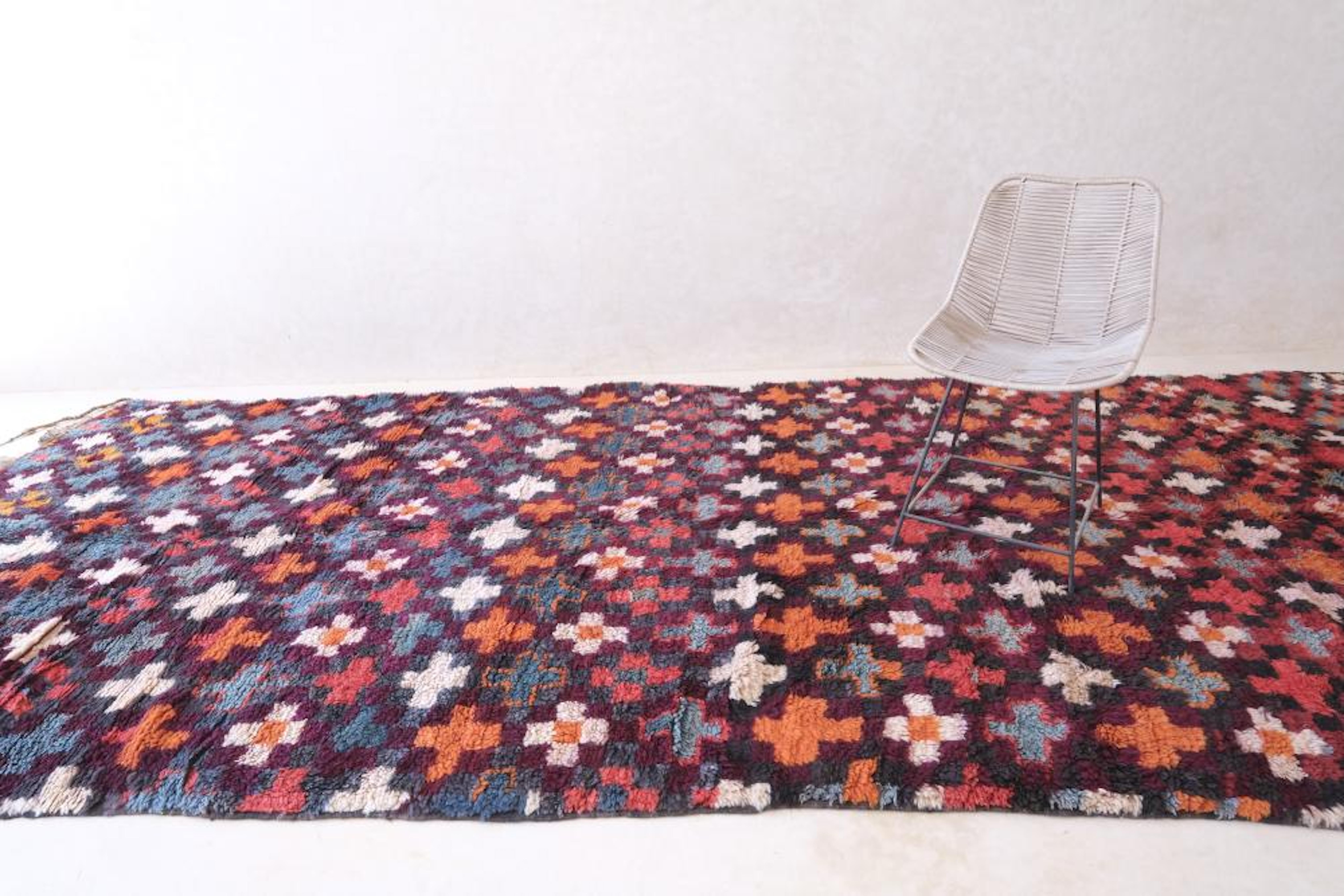 Ein ganz besonderer marokkanischer Vintage-Teppich vom Stamm der Beni M'Guild, der als Sammlerstück gilt. Dieser farbenprächtige Teppich oder Läufer zeichnet sich durch ein sich wiederholendes Kreuzmuster und einen karierten Rand aus. Dieses