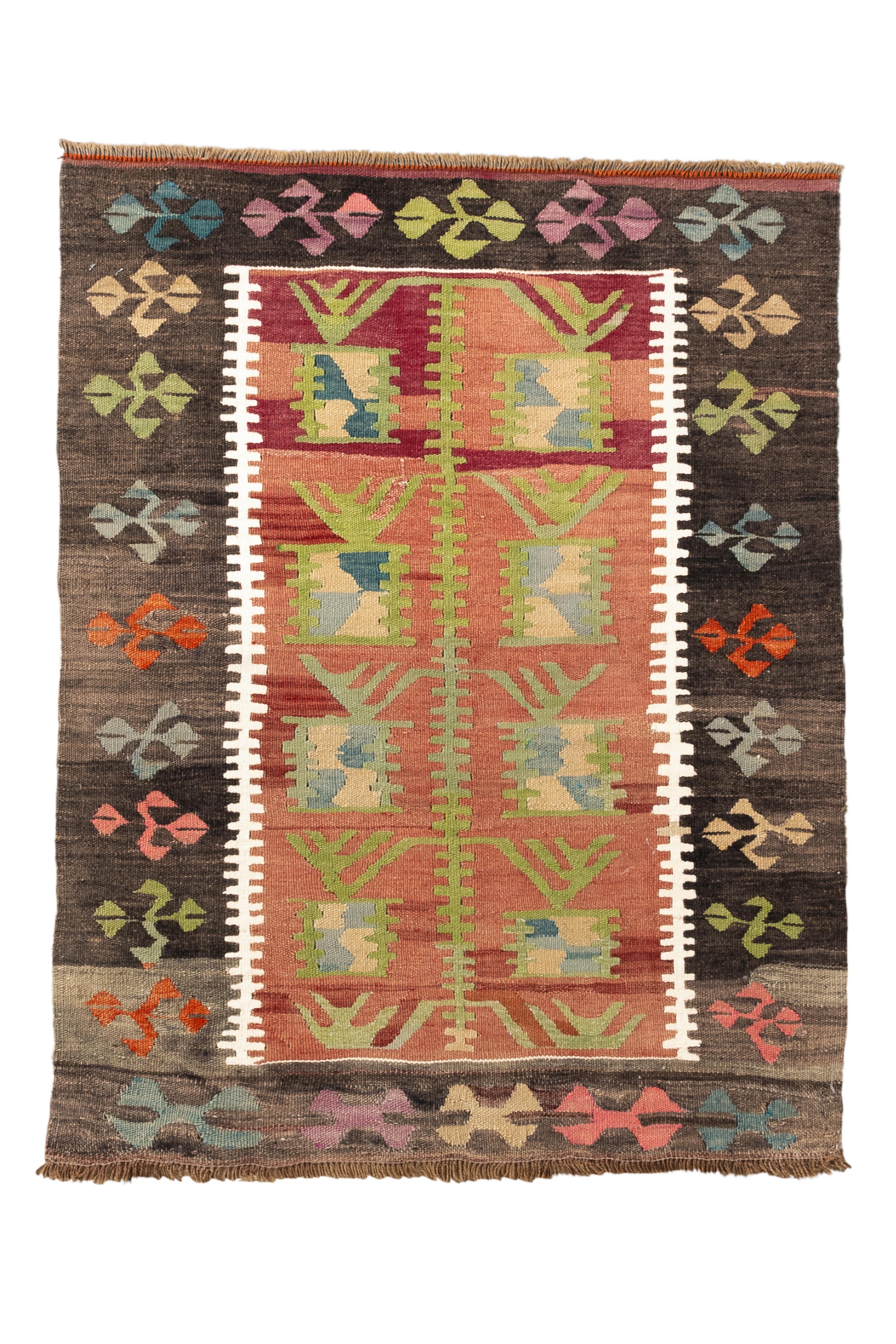 Dieser türkische Kelim im Vintage-Stil zeichnet sich durch eine verspielte Komposition aus übereinander gestapelten geometrischen Motiven und leuchtenden Farbblöcken aus. Die zentrale Terrakottaplatte ist mit leuchtend grünen, blassblauen,