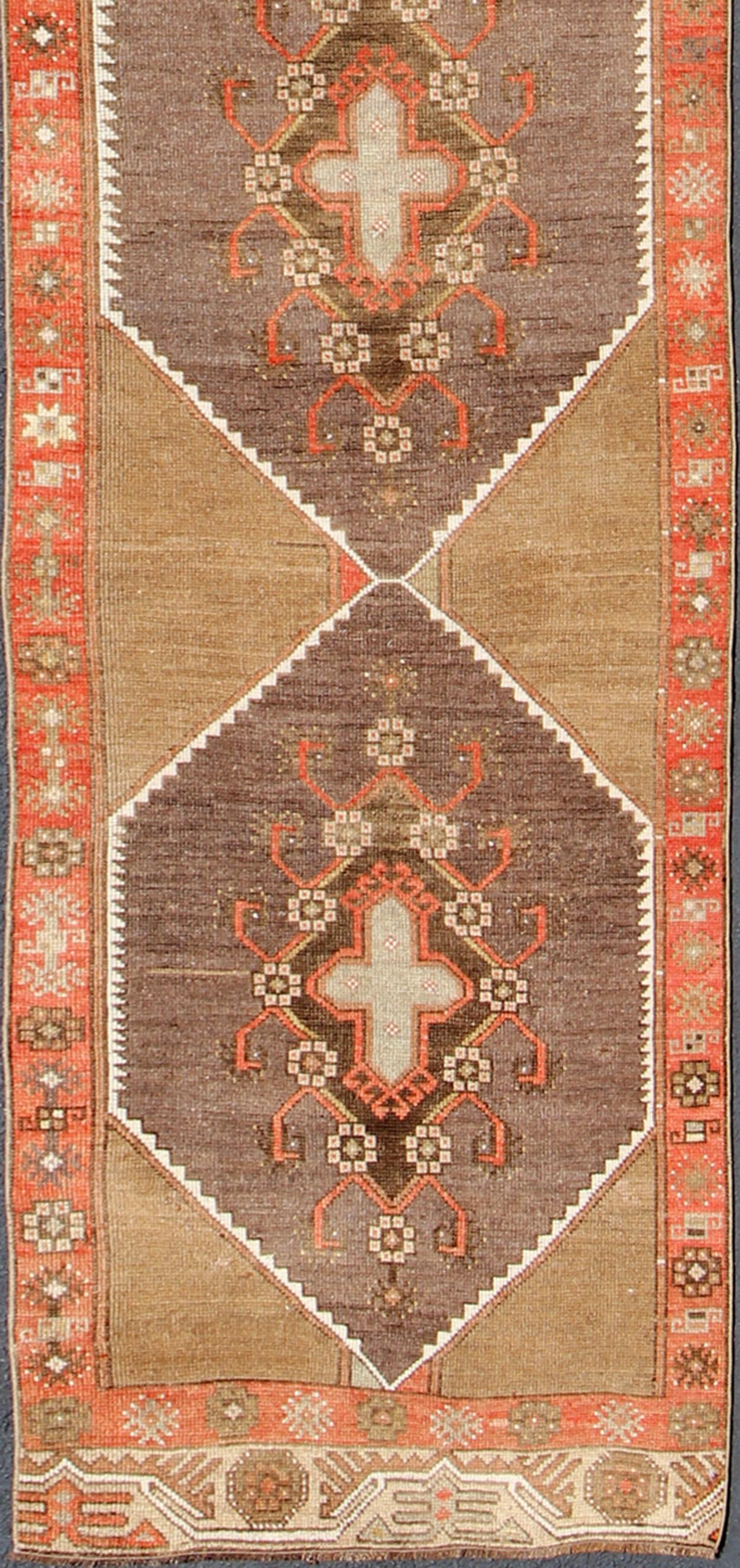 Tapis de course vintage long et étroit de Turquie avec un motif de médaillons géométriques à losanges multiples sur fond camel, rouille, gris, orange, brun et taupe. tapis/TU-UGU-4808, pays d'origine / type : Turquie / Oushak, circa 1930

Ce tapis