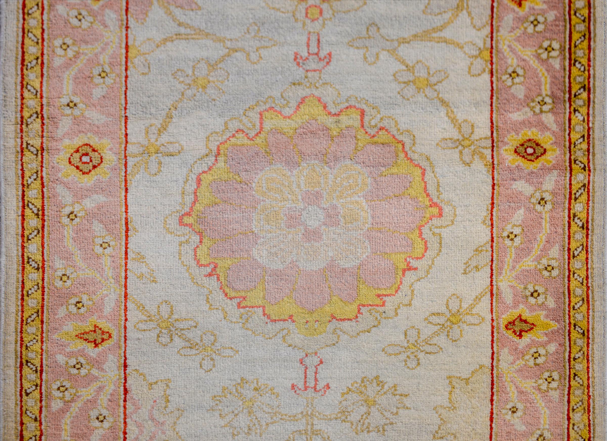 A colossal early 20th century Turkish Oushak runner with multiple round floral medallions rendered in lilac, gold, and crimson, on a pale indigo background with green scrolling vines and flowers. The border is simple, with a wide inner floral and