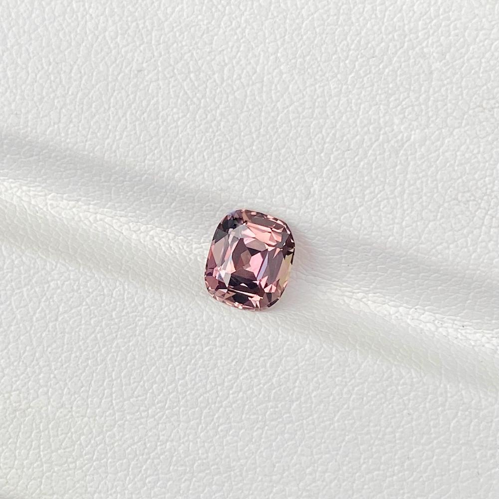 A ravishing peach sapphire with delicious warm overtones of pinkish orange creates a unique colour shift under incandescent light. Skilfully cushion cut using traditional methods this over 1.5 carat peach sapphire is a natural rare beauty of