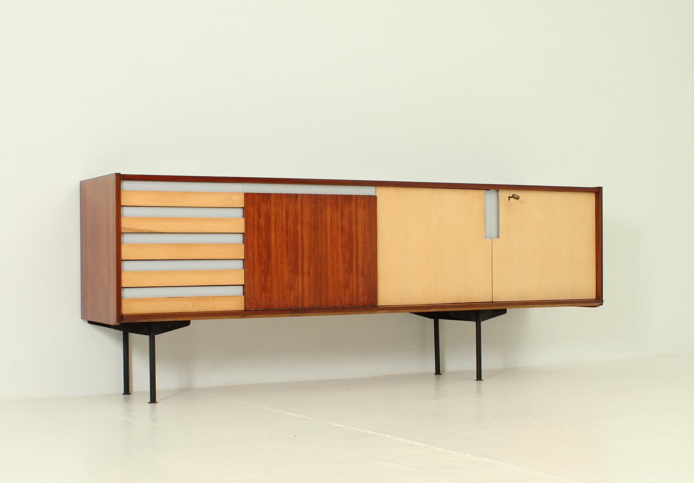 Italian sideboard from 1950's. Different types of woods and coloured laminated top and front details, base in black lacquered metal. Five drawers, one space with a folding door and double space with two doors and internal shelf.