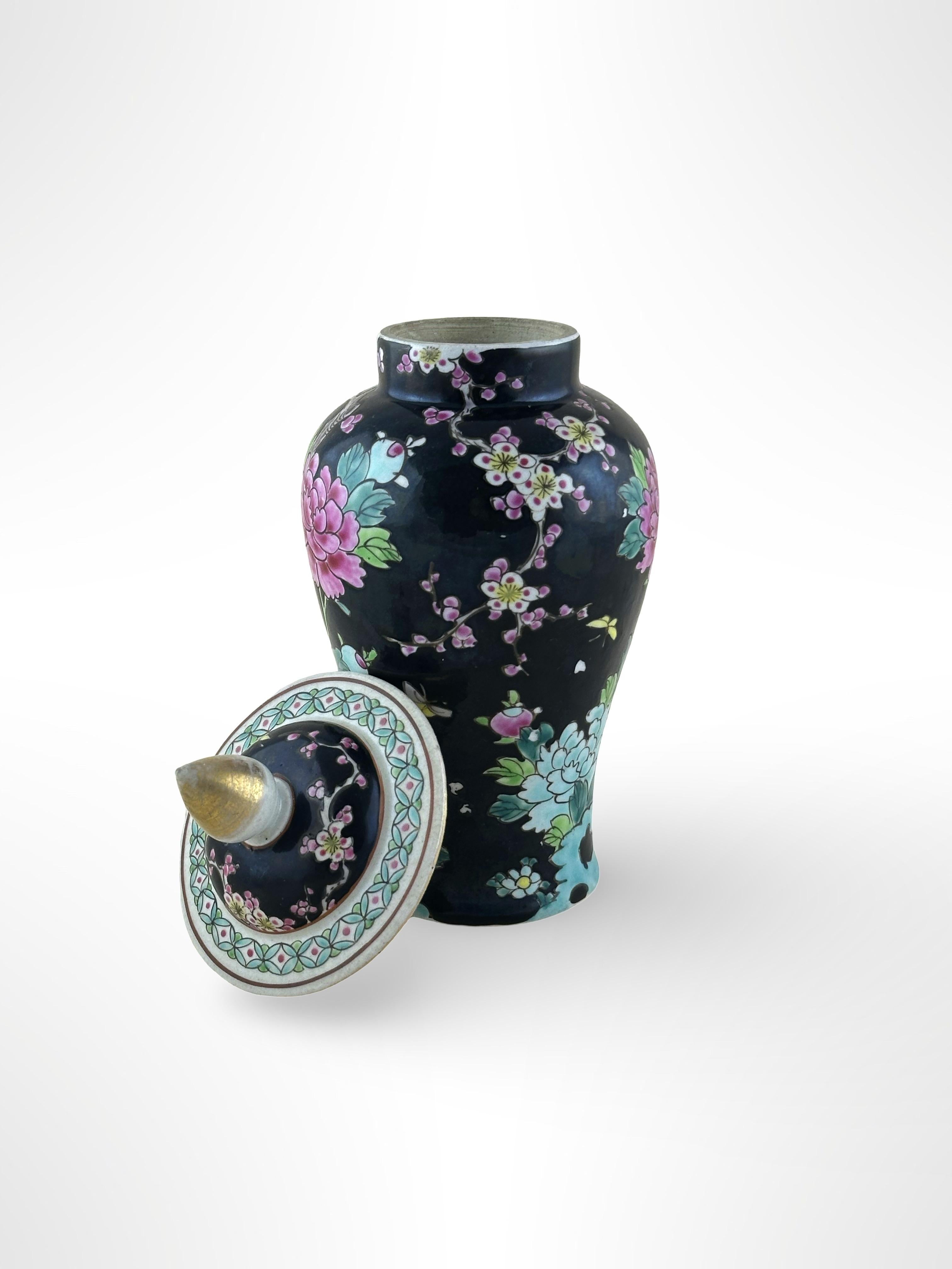 A bold 'famille noire' style porcelain temple jar.  Handcrafted in Japan at the beginning of the 20th century, towards the end of the Meiji period.

The little porcelain temple jar is hand-painted with a landscape of flowering peony blossoms and