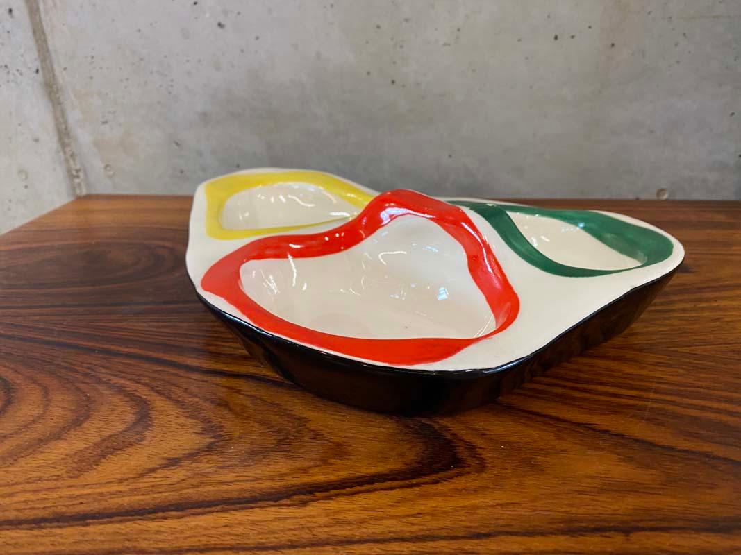 Ceramic bowl by the artist and designer Roland Brice (1911-1989). The ceramic is organically shaped, painted white and has three depressions, whose edges are decorated with the colors red, green and yellow. The outer edge of the bowl is edged in