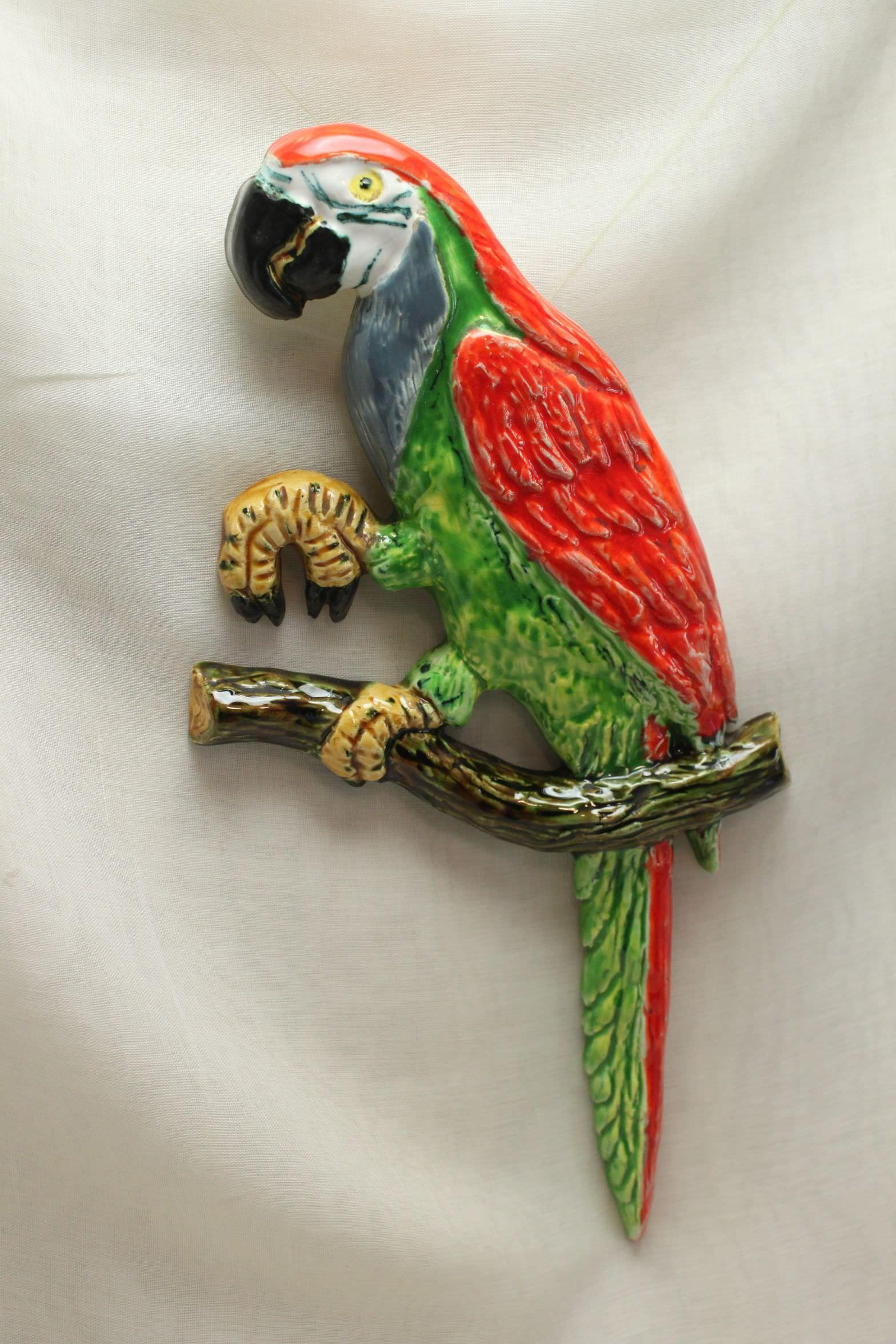 This colourful parrot wall decoration, or wall hanging is made of earthenware and measures 350 mm (13.75 inches) in height, 178 mm (7 inches) in width and 28 mm (1 inch) in depth. It is in very good condition, and would probably date from the 1950's.