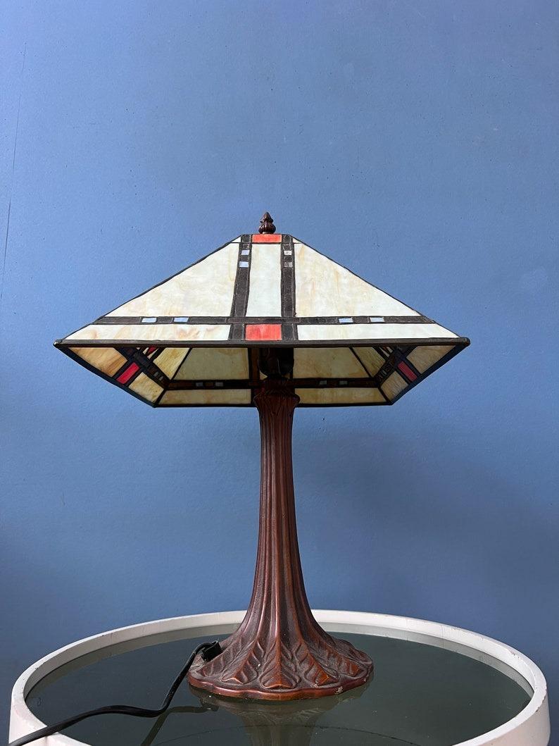 Lampe de table Bigli avec abat-jour en verre teinté coloré. La base est en métal et l'abat-jour est en acrylique. Le vitrail crée un magnifique effet de lumière. L'abat-jour peut être retiré de la base et positionné de la manière souhaitée. La lampe