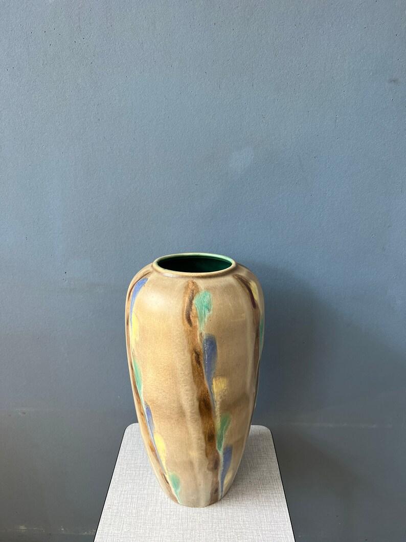A vintage murano style glass or vase. The vase has a beige/brownish surface colour with elements of blue, yellow and turquoise

Additional information:
Materials: Ceramic
Period: 1970s
Dimensions: Diameter: 24 cm
Height: 59 cm
Condition: Very good.
