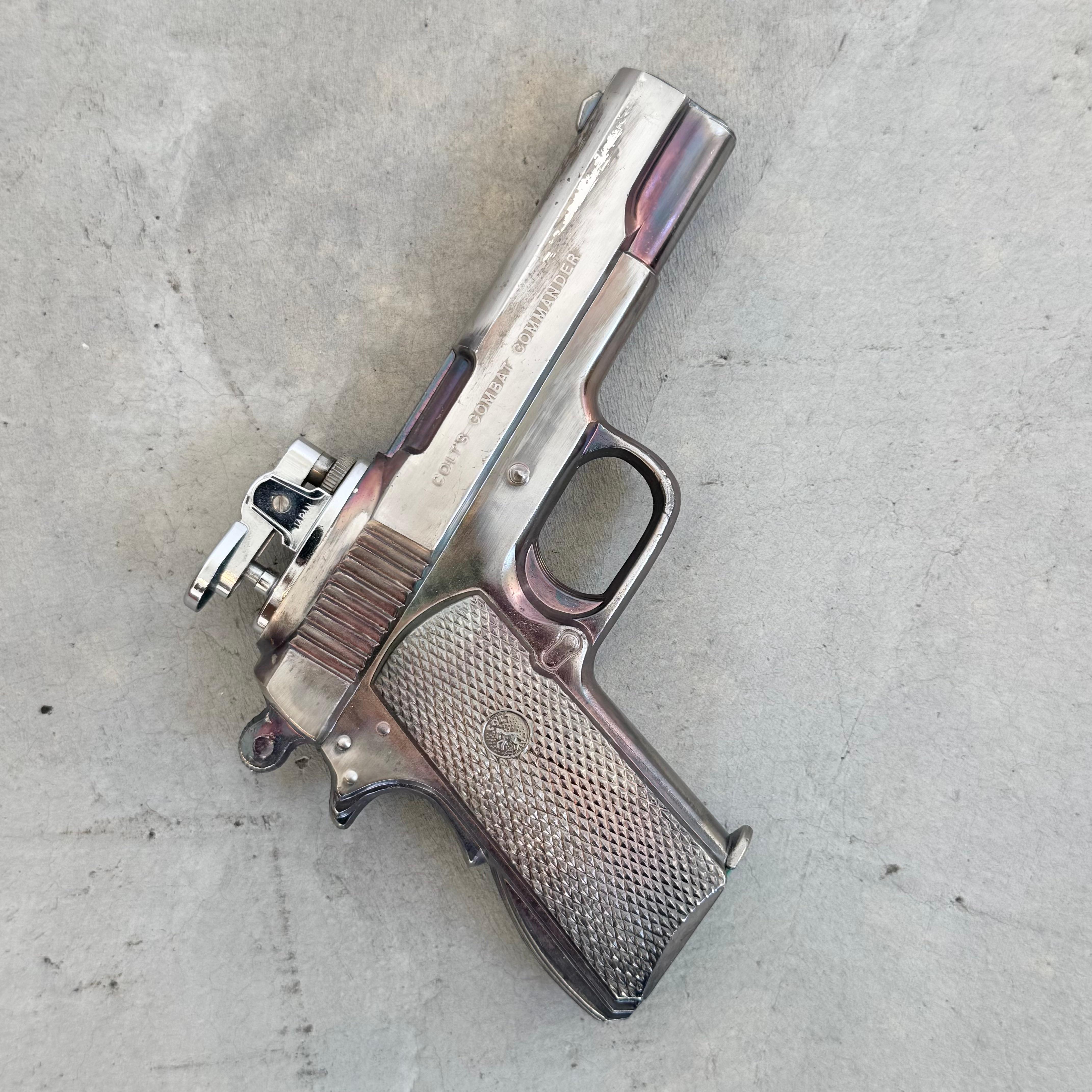 This handsome lighter is cast in the shape of a Colt Combat Commander handgun. Perfect for any collector of smoking paraphernalia or firearm enthusiast. Relieved lettering on the right side of the barrel reads 'Colts Combat Commander', while the